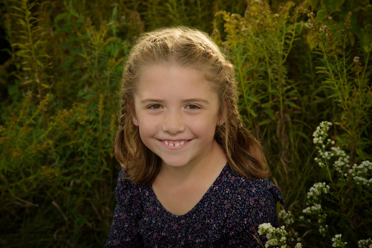 Portrait of a young girl sitting in a long grassy field at Fonferek Glen County Park near Green Bay, Wisconsin