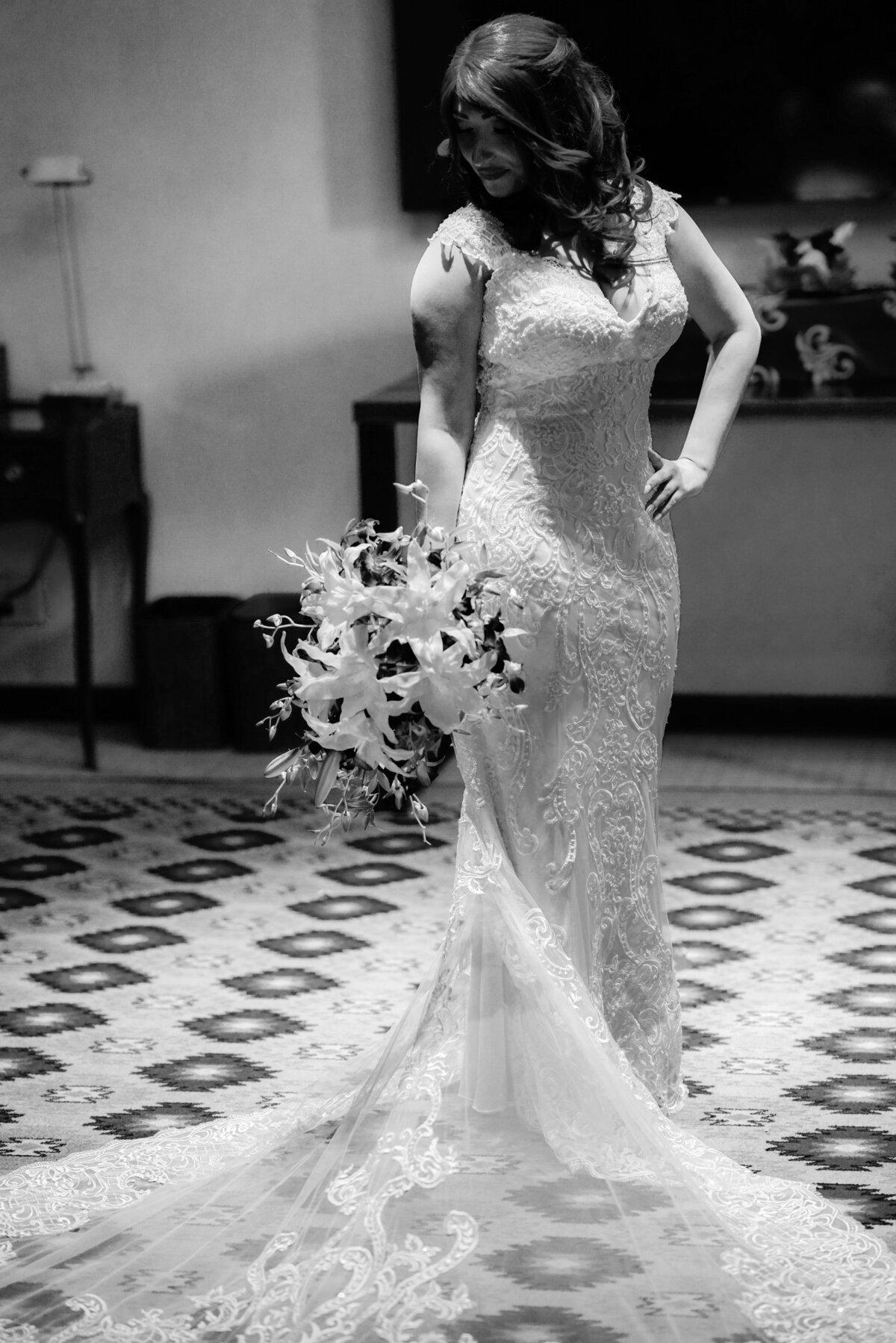 A black-and-white image of a bride in her wedding dress, showcasing the timeless elegance and classic beauty of her attire. This monochrome portrait emphasizes the intricate details of the gown and the bride's graceful demeanor, highlighting the sophistication of the moment.