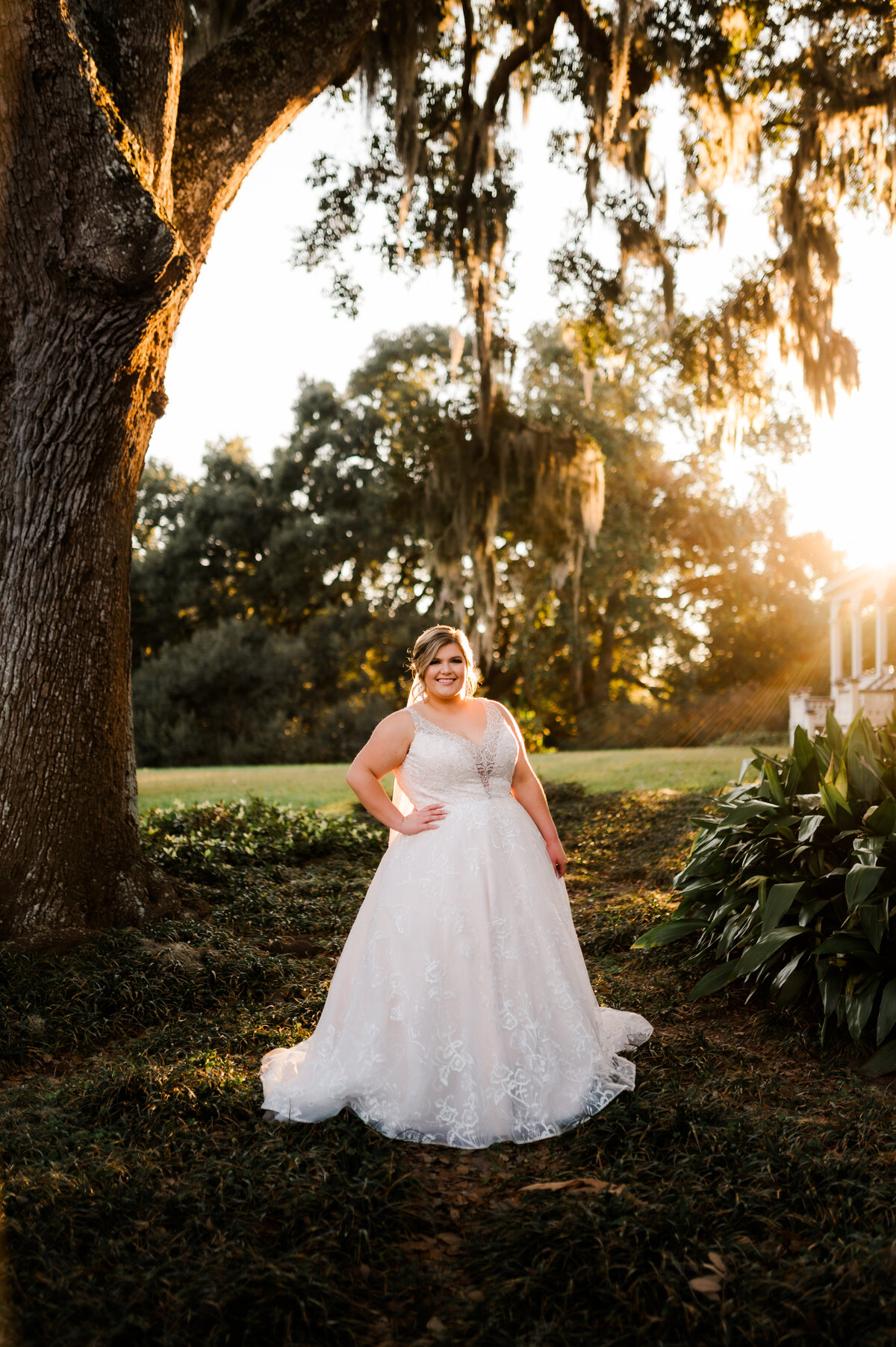 outdoor bridal photos with the sun setting behind the bride as she stands next to mossy trees captured by Little Rock wedding photographer