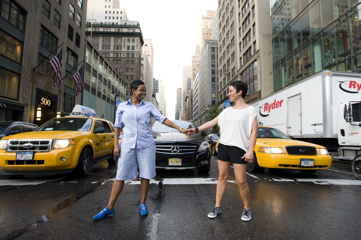 A couple reaching out and holding hands in the middle of a city street 