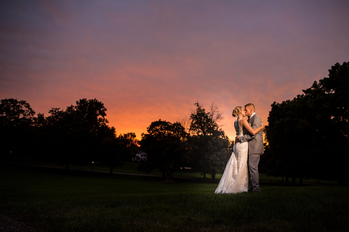 couplle embrace Fieldcrest Estate in front of red sky sunset