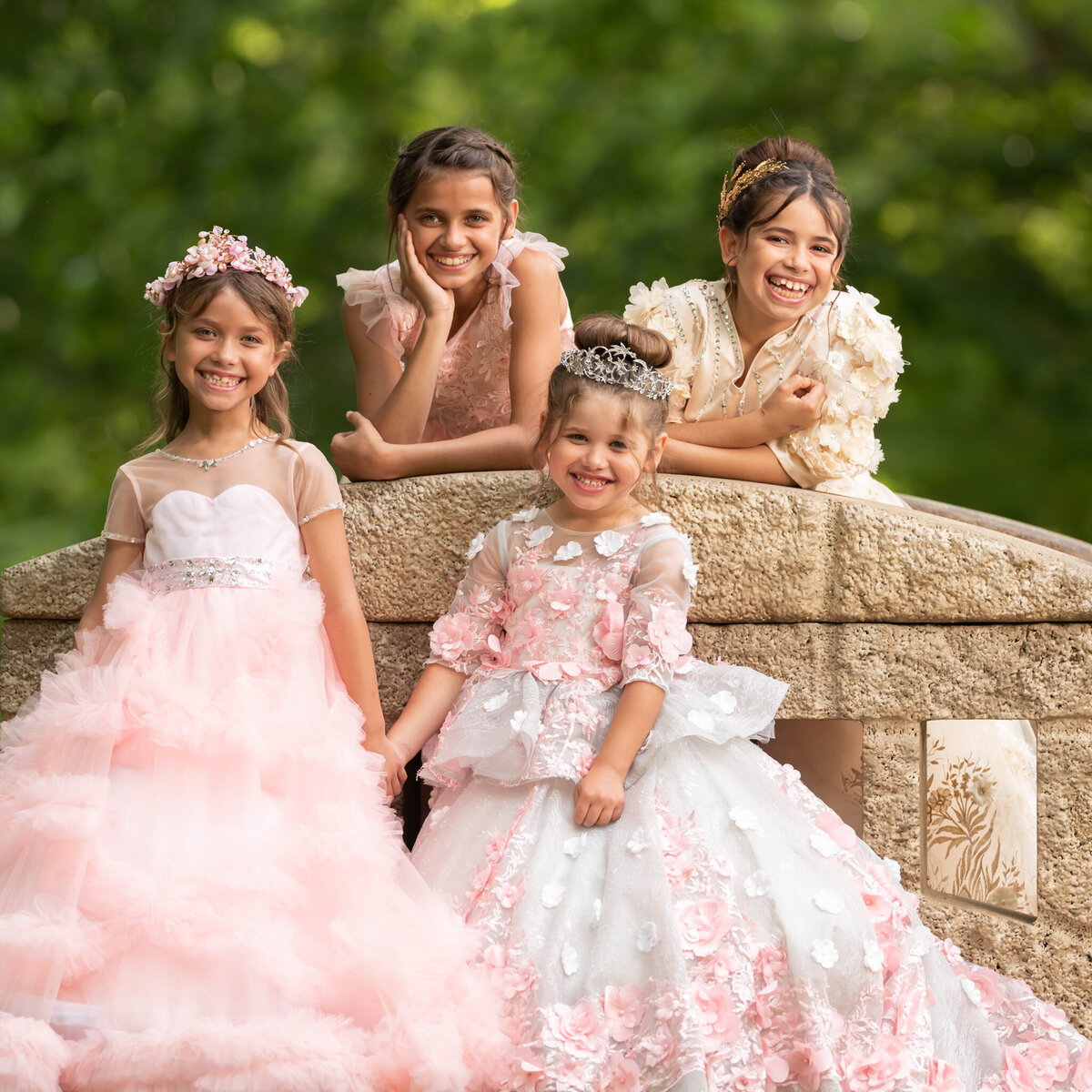 Elegant outdoor portrait of three sisters in beautiful pink and white gowns, posed on a stone bridge. Captured in Leawood, Kansas, this sophisticated setup is ideal for families seeking timeless sibling photography.