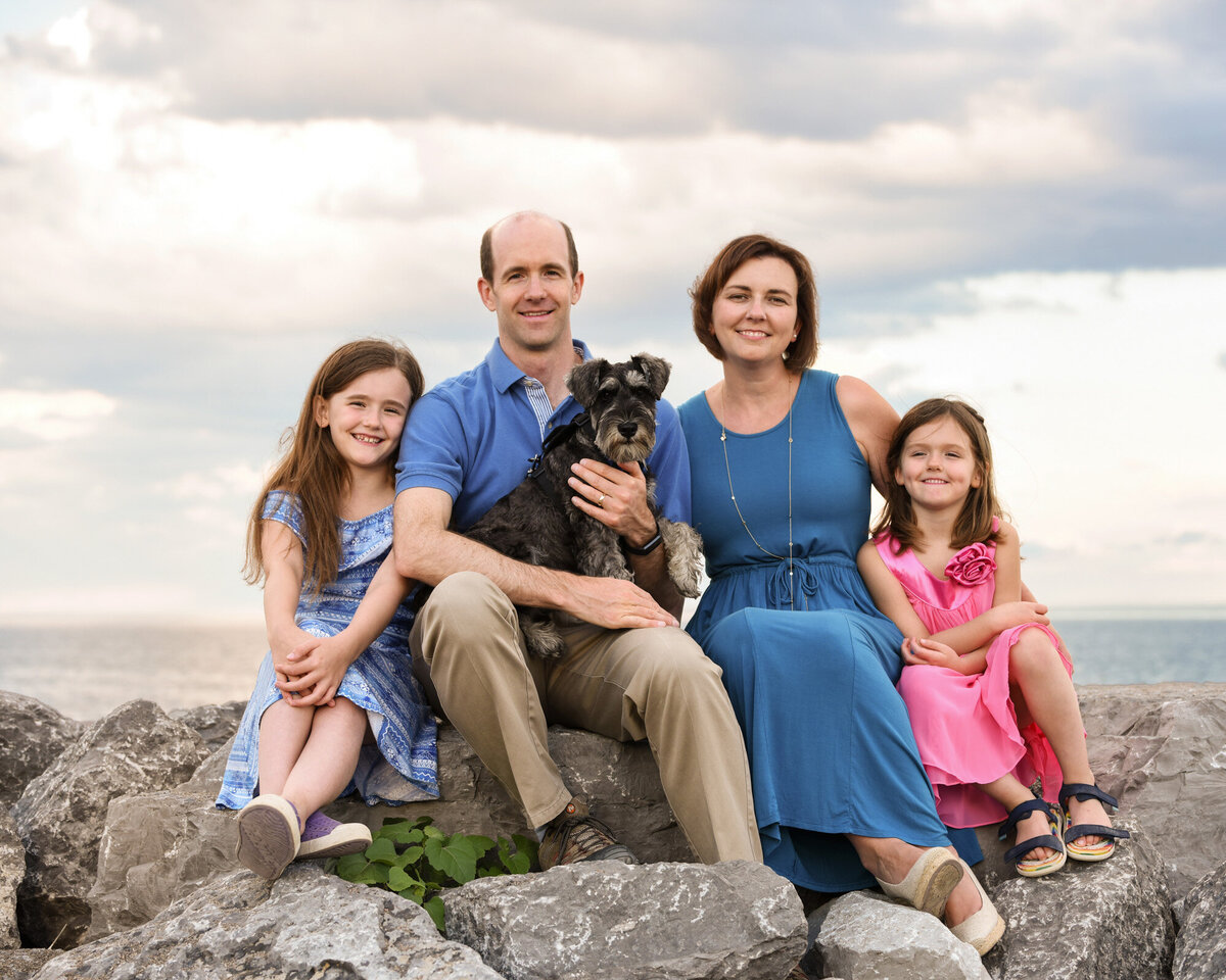 Family sitting on beach rocks with dog overcast day