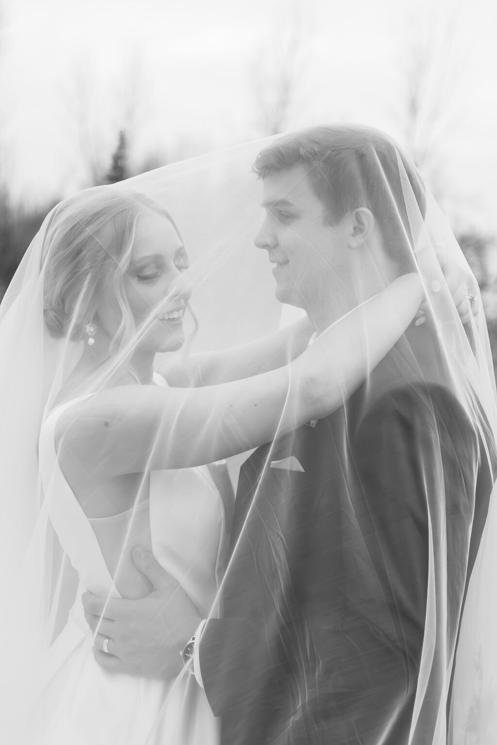 bride and groom posed under bridal veil