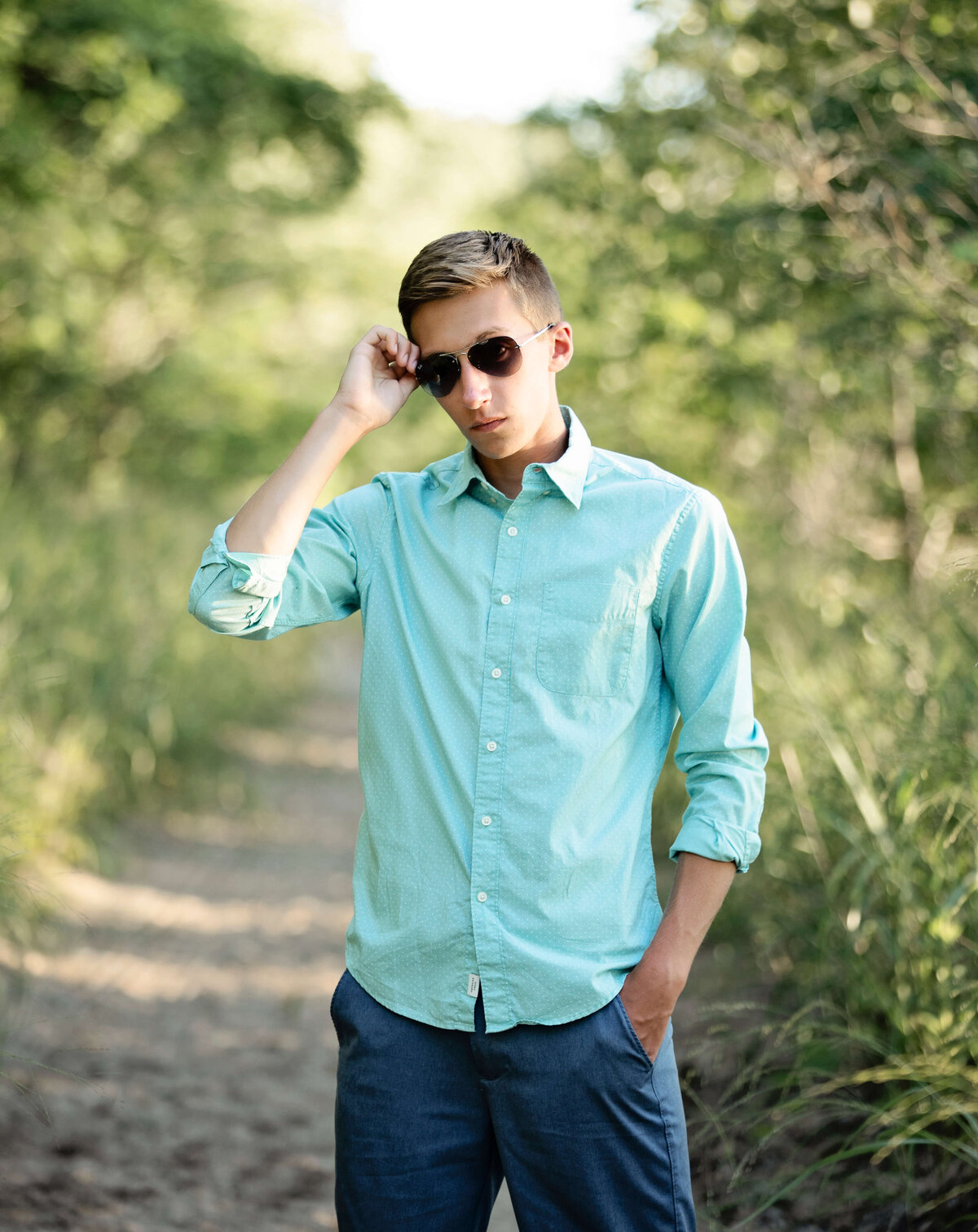 Senior photo of a boy in sunglasses standing in the sand at the Peninsula in Erie Pa