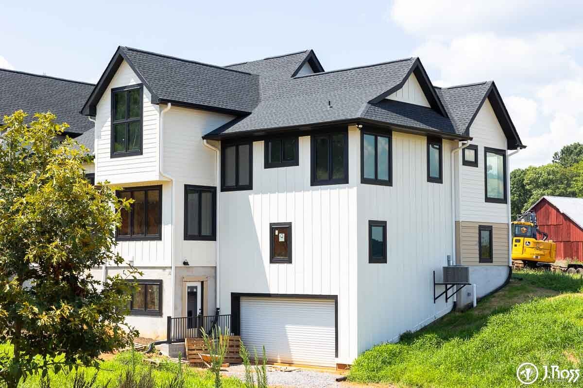 Corner view of the white modern farmhouse exterior with black trim, dark roof, and a basement-level garage, demonstrating superior home outside painting, Kingsport, Tennessee.