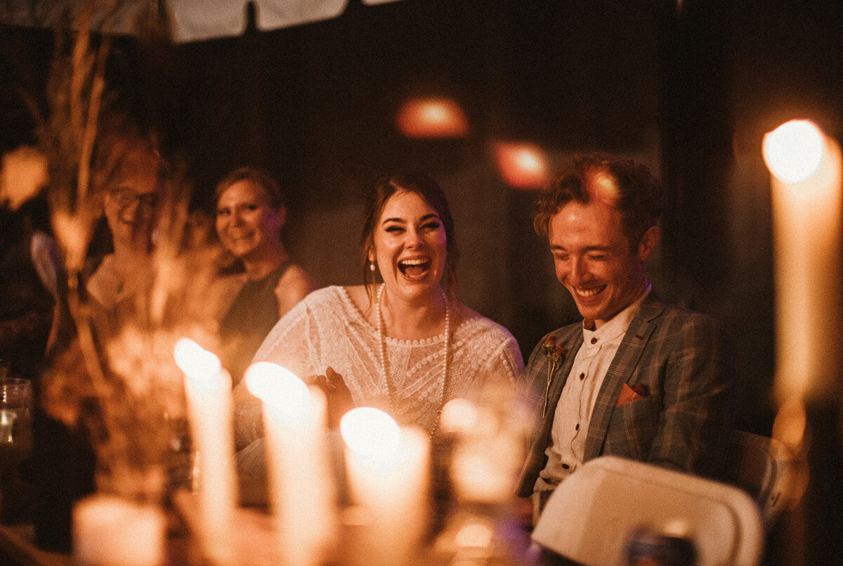 couple candidly laughs amongst candlelight in boston backyard wedding