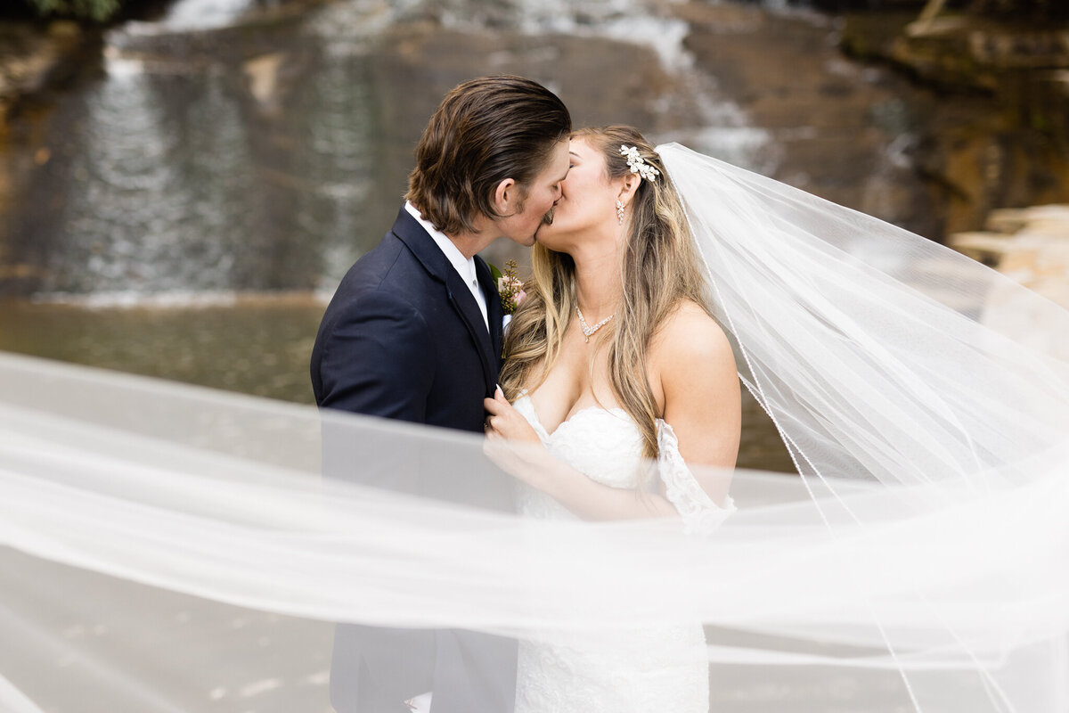 Elegant wedding at Chota Falls in North Georgia  - bride and groom kiss with veil swoop