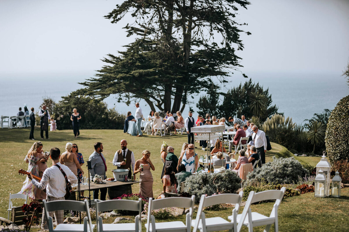 A group of people enjoying an outdoor drinks reception on the lawn