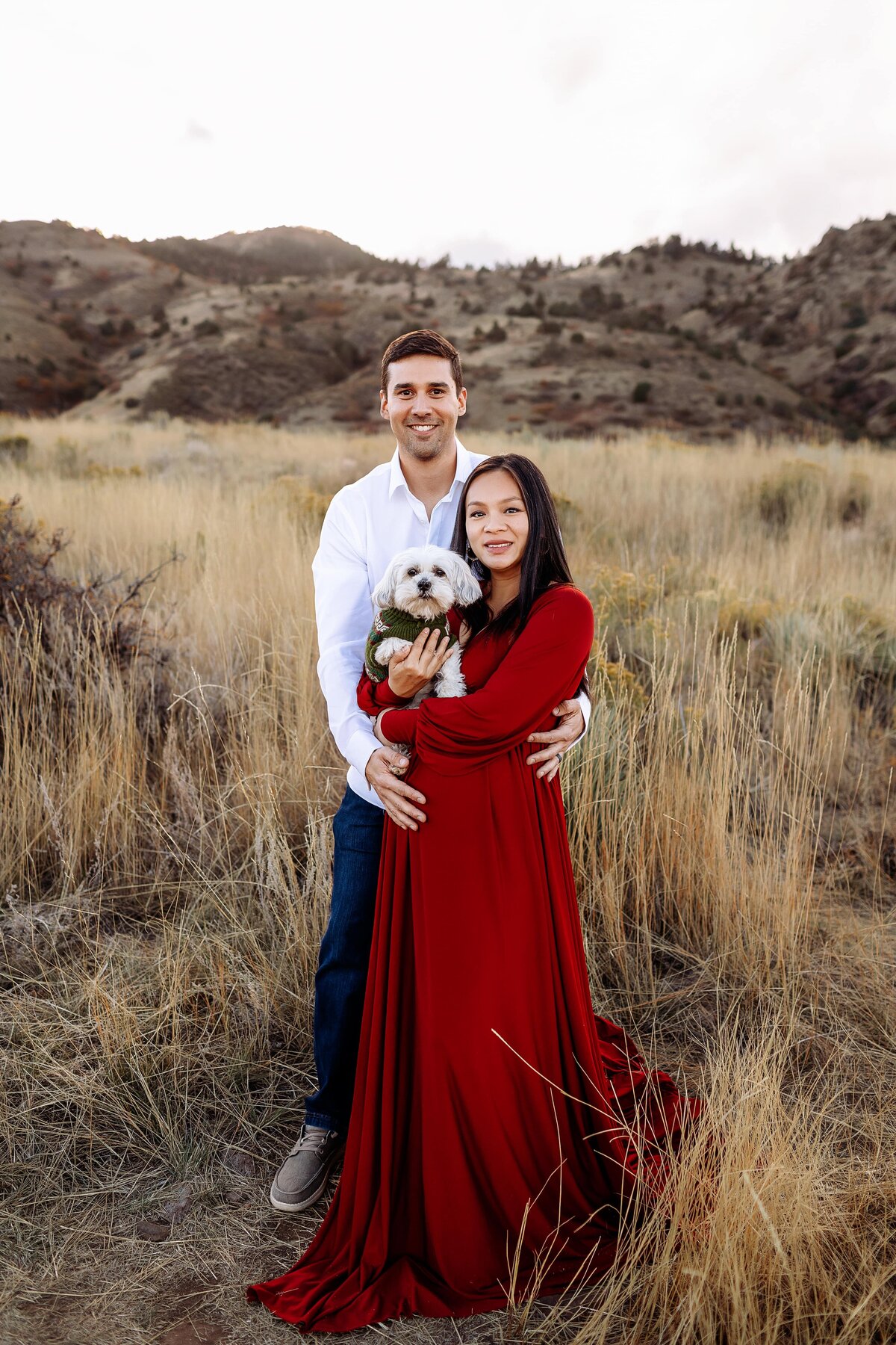 couple expecting their first child posing in front of red rocks in morrison, colorado before their baby arrives