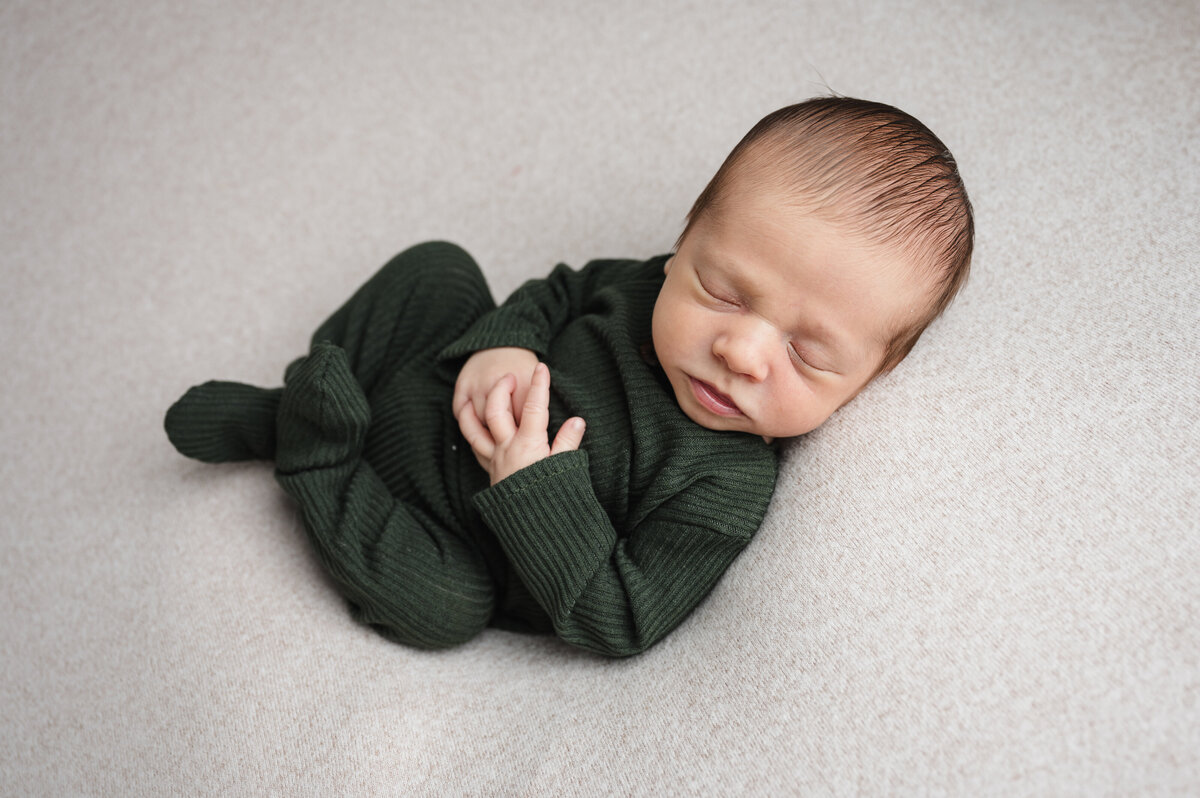 This adorable newborn baby session in Pittsburgh, PA captures the baby boy dressed in a cozy green knit outfit. The soft tones and peaceful expression showcase the timeless charm of newborn photography.