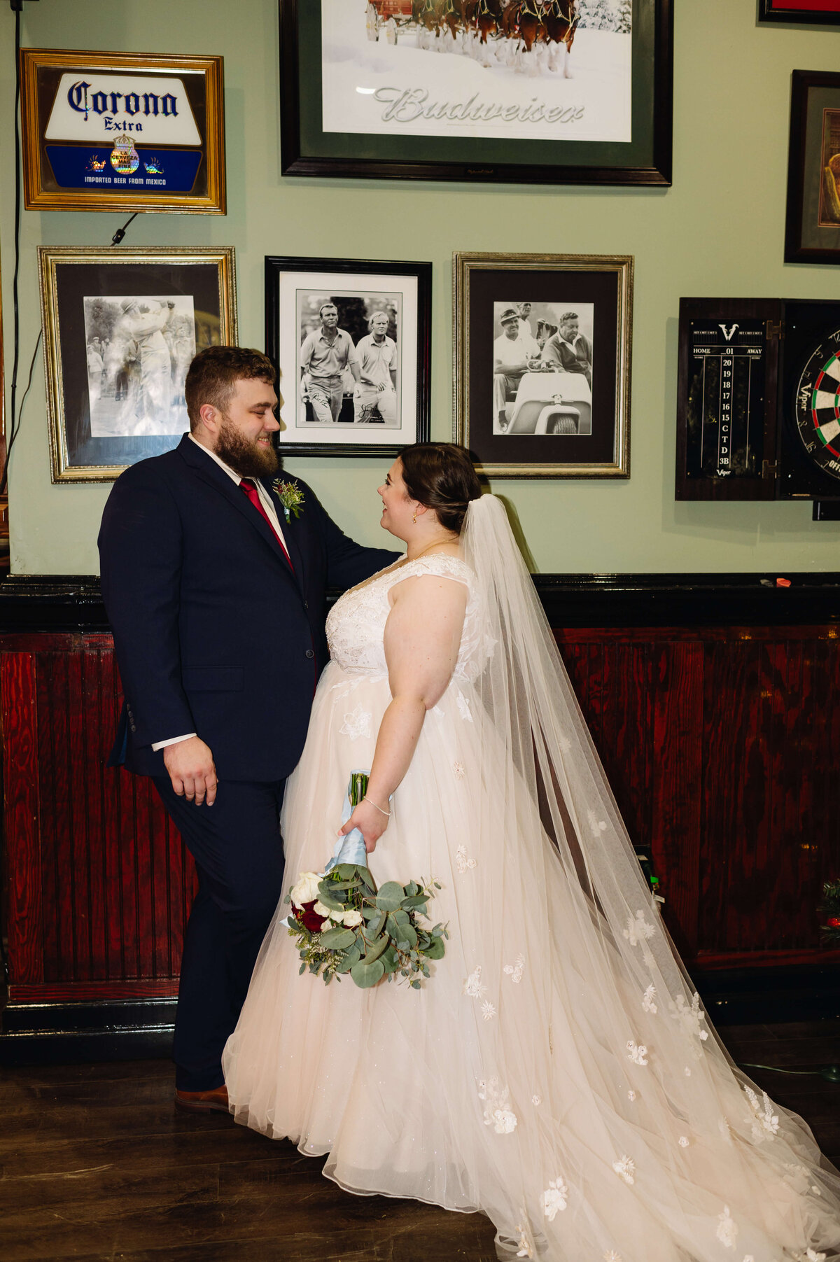 bride and groom posing together in a grand room together adorned with historic pictures in vintage frames at brandermill country club