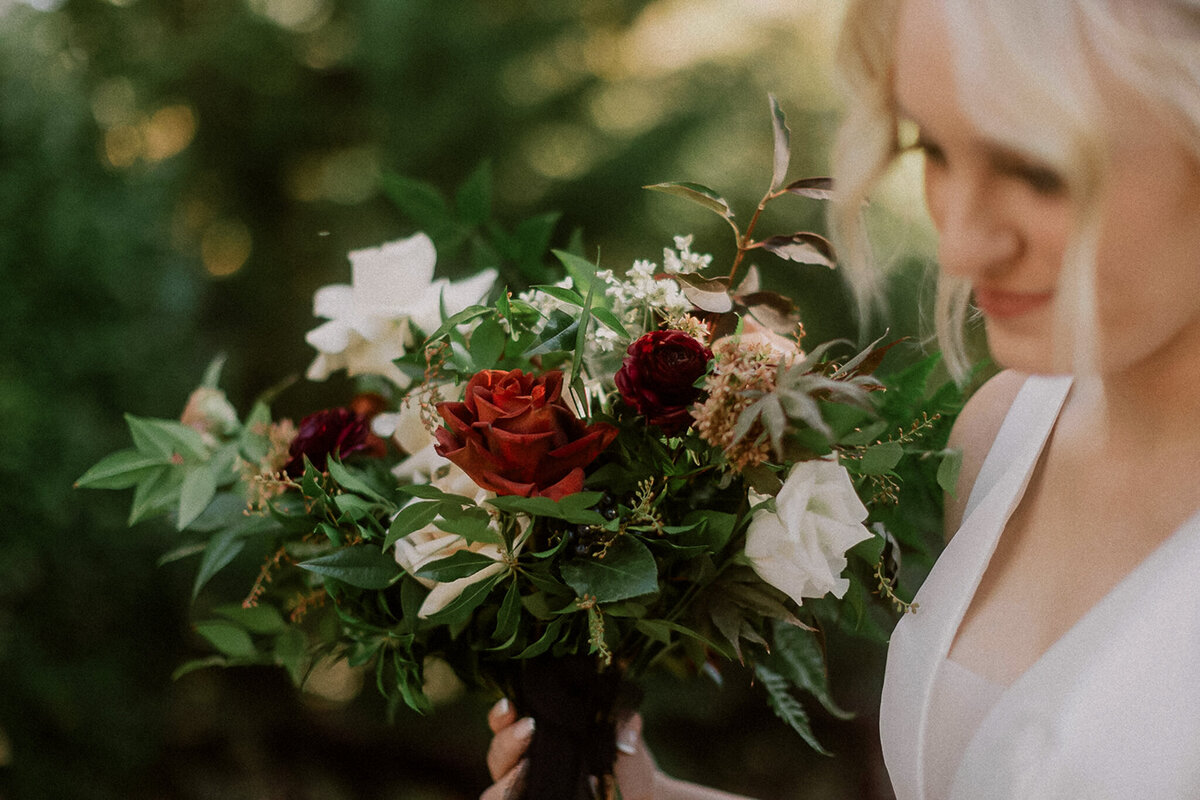 Bride walks through the greenery with her bouquet