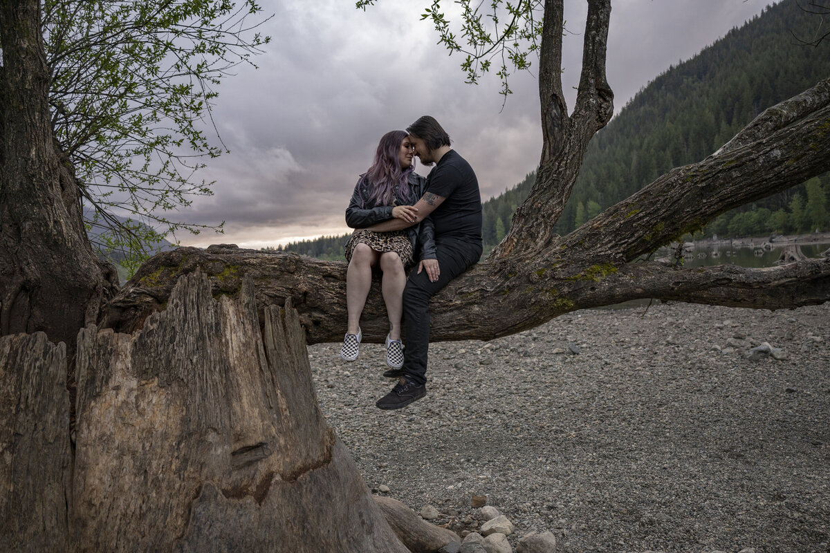 Couple sitting up on a large tree branch at Rattlesnake Lake in Washington.