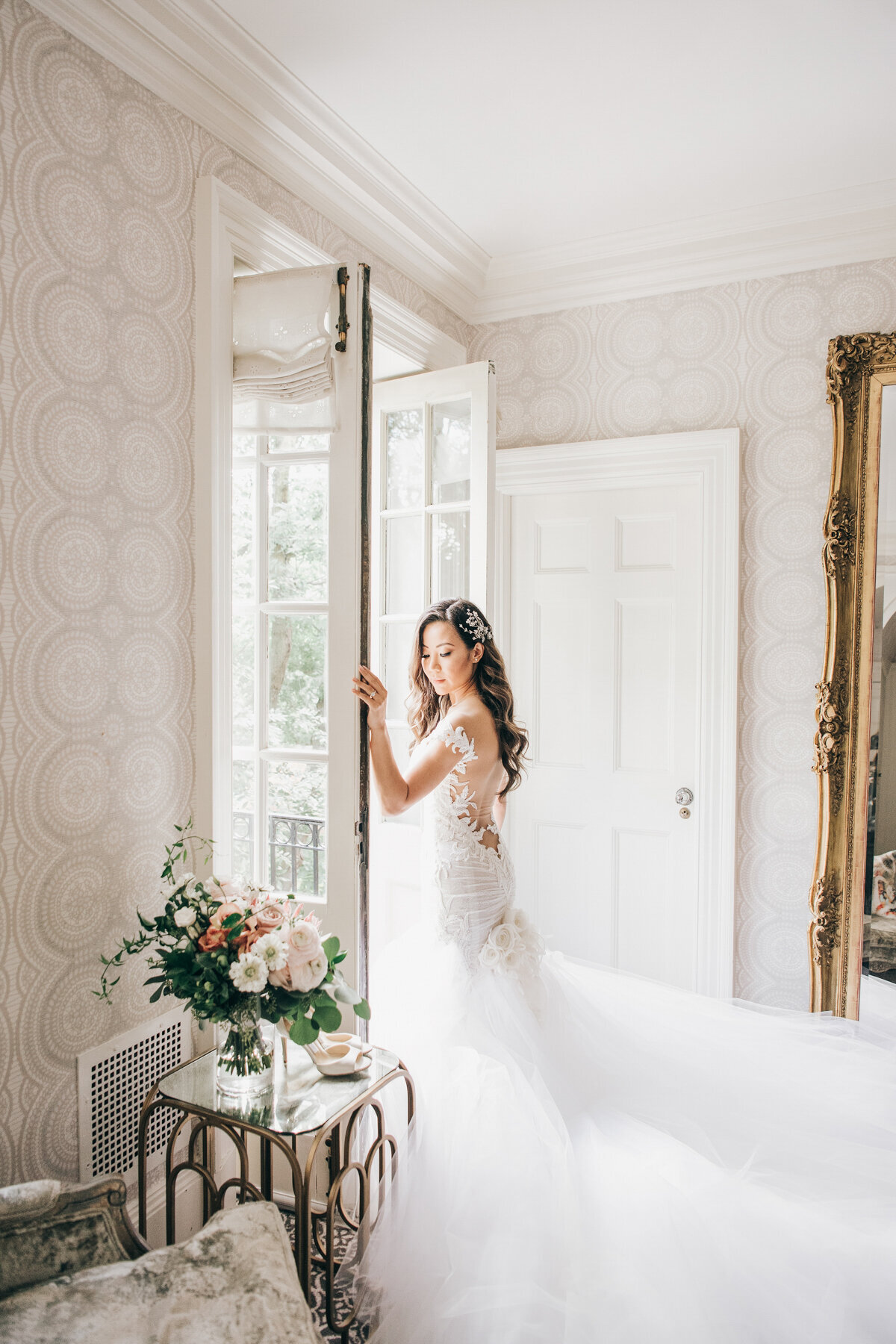 Glamorous portrait of bride opening french doors