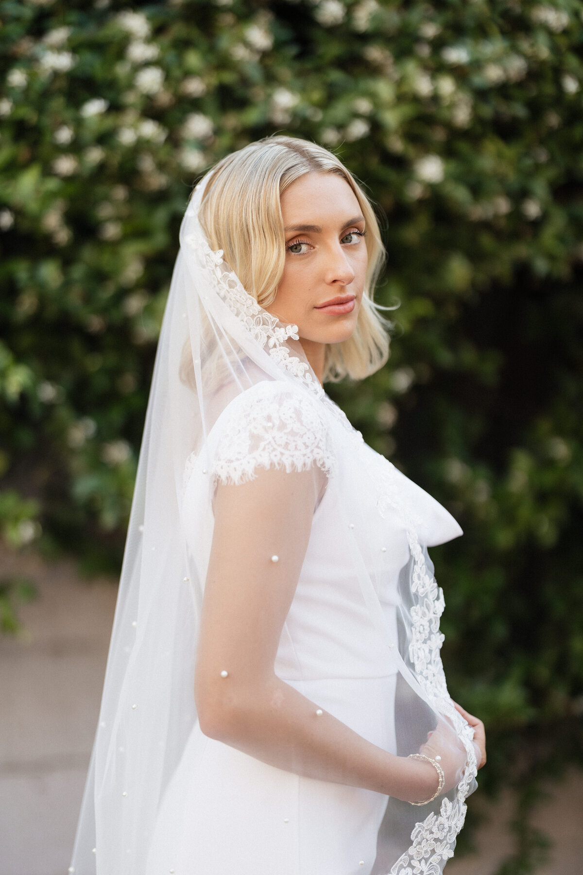 Bride staring into the camera with her veil over her shoulder.