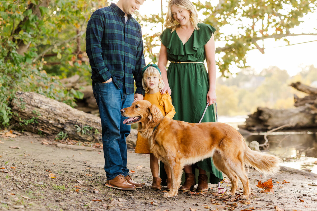 Fall family portrait with dog next to river bank.
