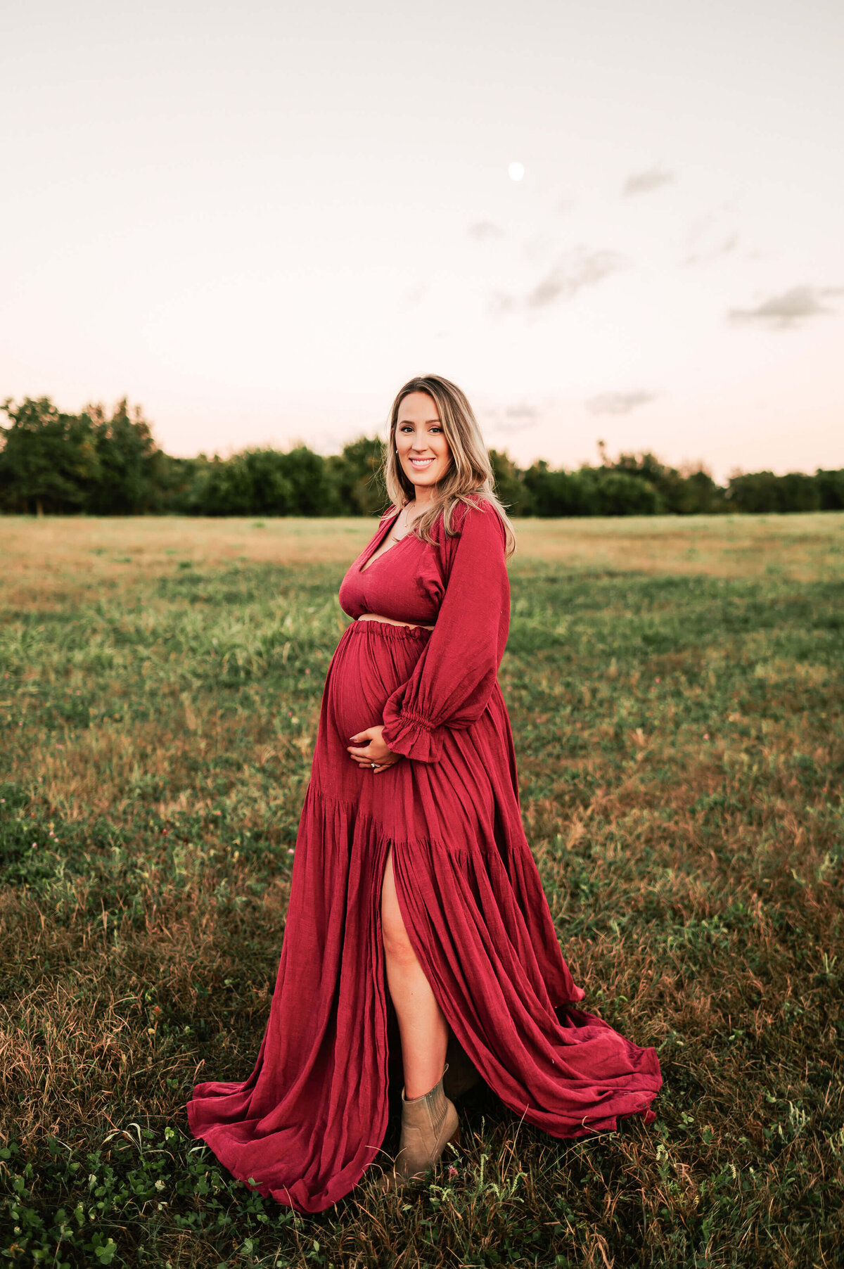 pregnant mom smiling in open field in Springfield MO at sunset