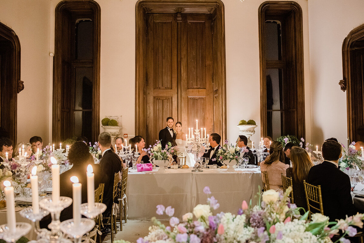 Bride and groom giving a heartfelt speech during their wedding dinner in the hall of Château Challain, captured in elegant, romantic wedding photography.