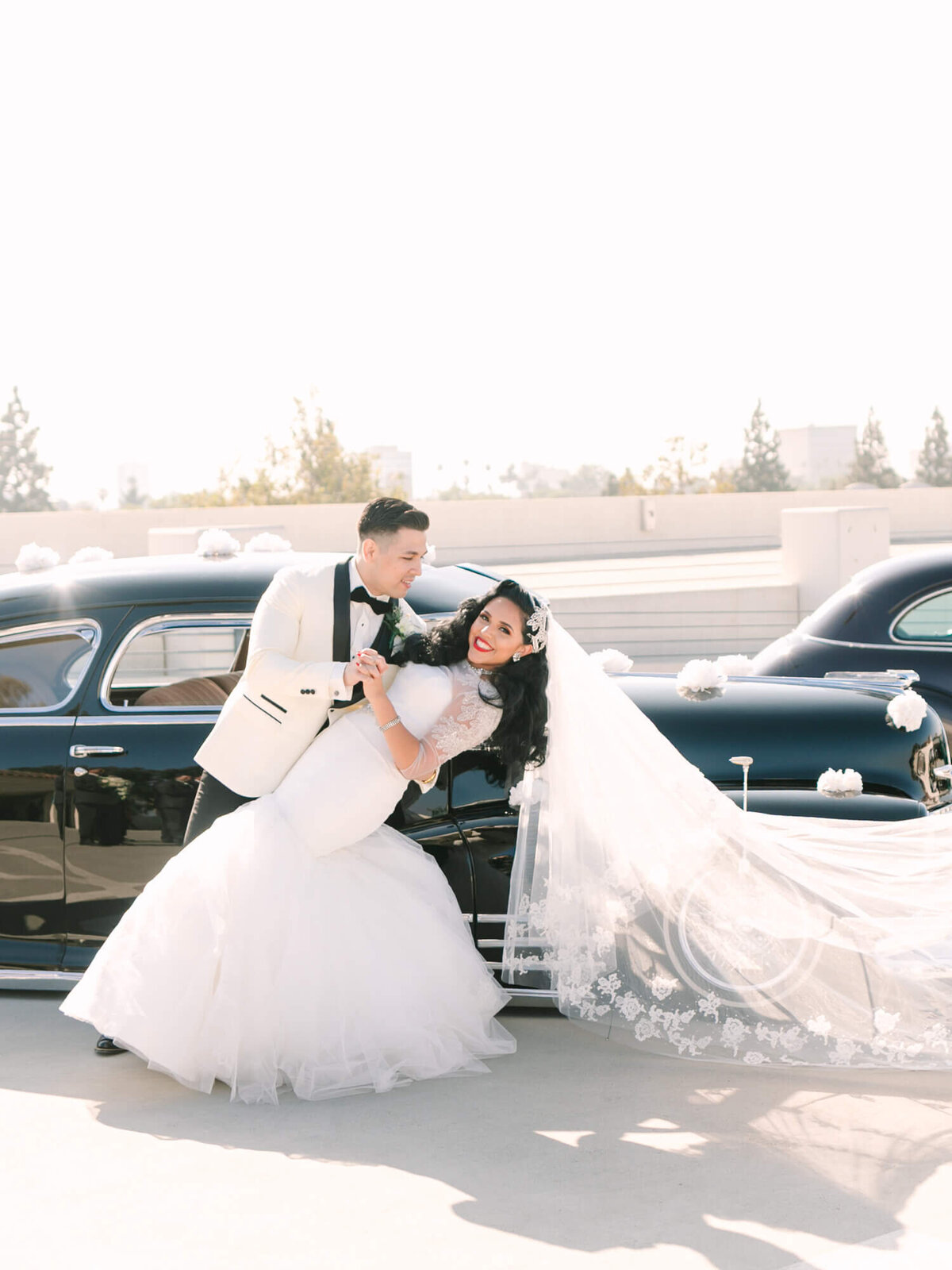 wedding photography of bride and groom dipping in front of classic car