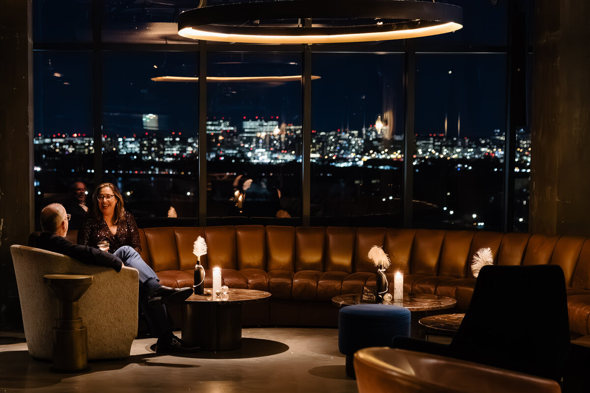 a candid portrait of an elegant couple during a corporate event holiday party in a luxury lounge overlooking the city of DC- Brandgo photography corporate event photographer  