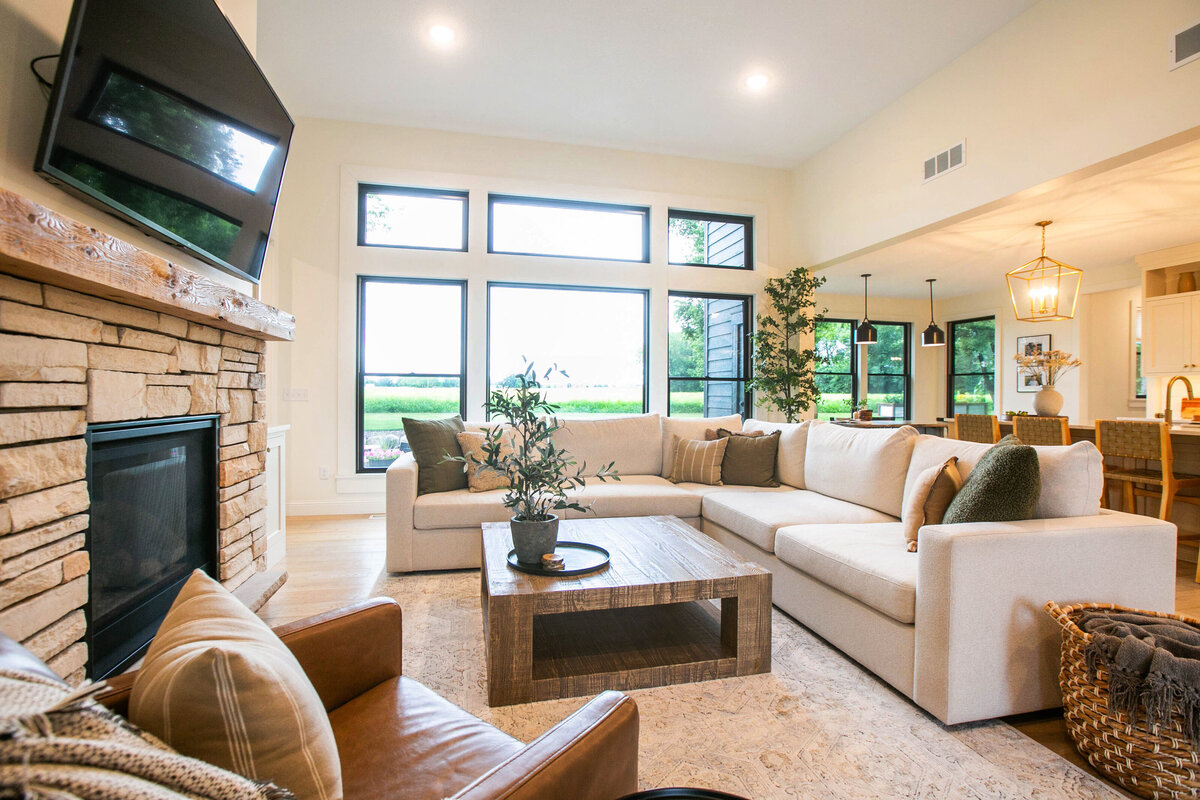 Cozy living room in Otsego custom home with fireplace, built-ins, and large windows