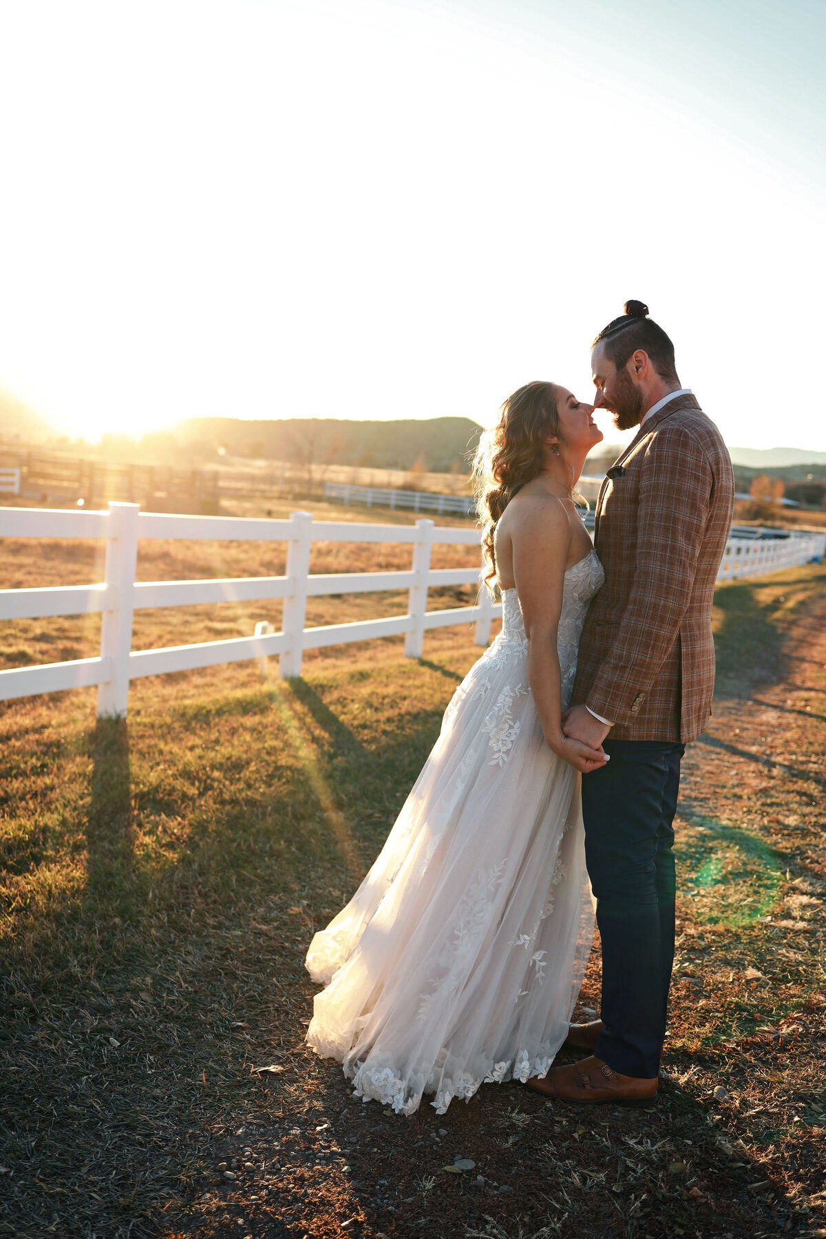 A golden hour moment between a bride and groom, dancing in the light and smiling at each other,
