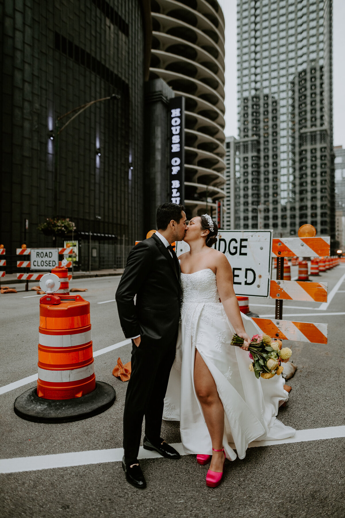 A bride and groom kiss in front of a bridge closed sign in downtown Chicago.