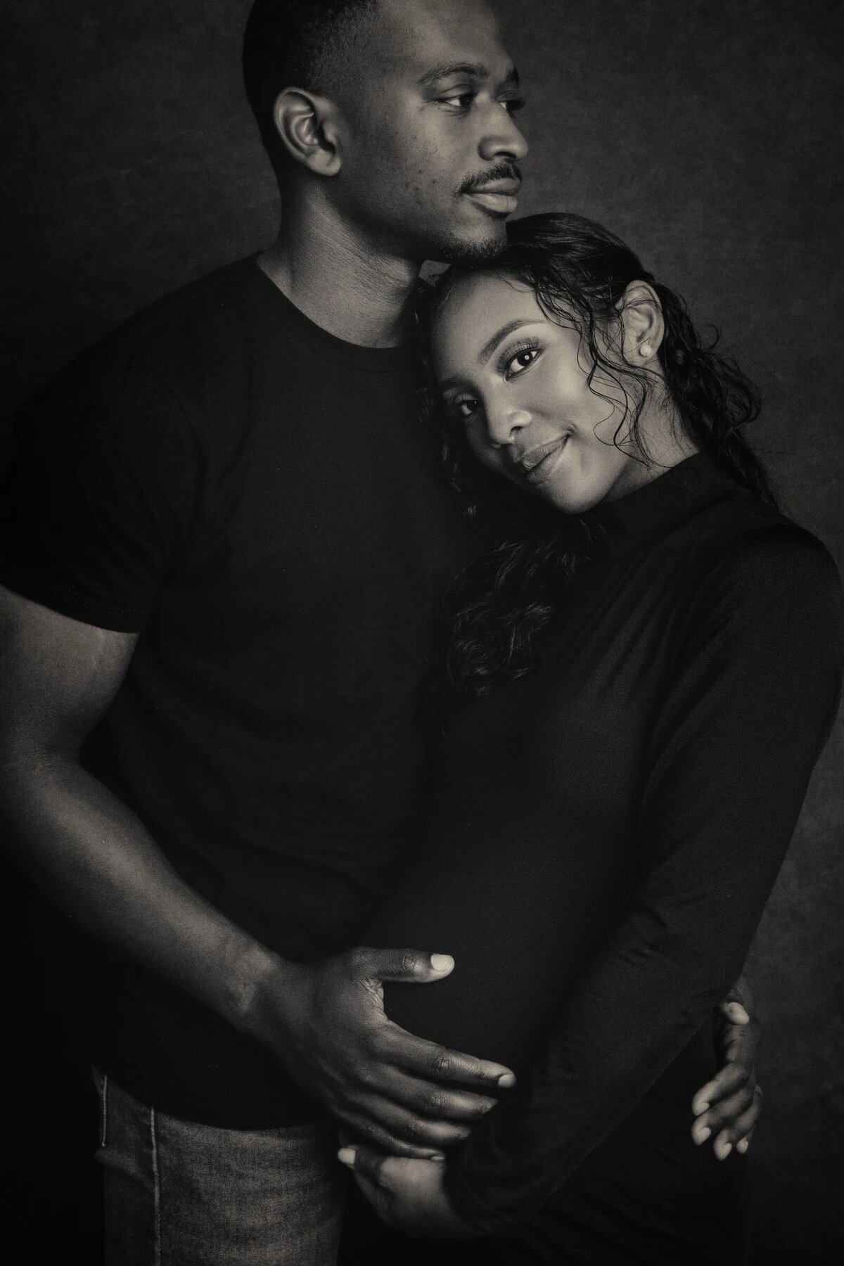 A man hugging a woman and holding her baby bump.