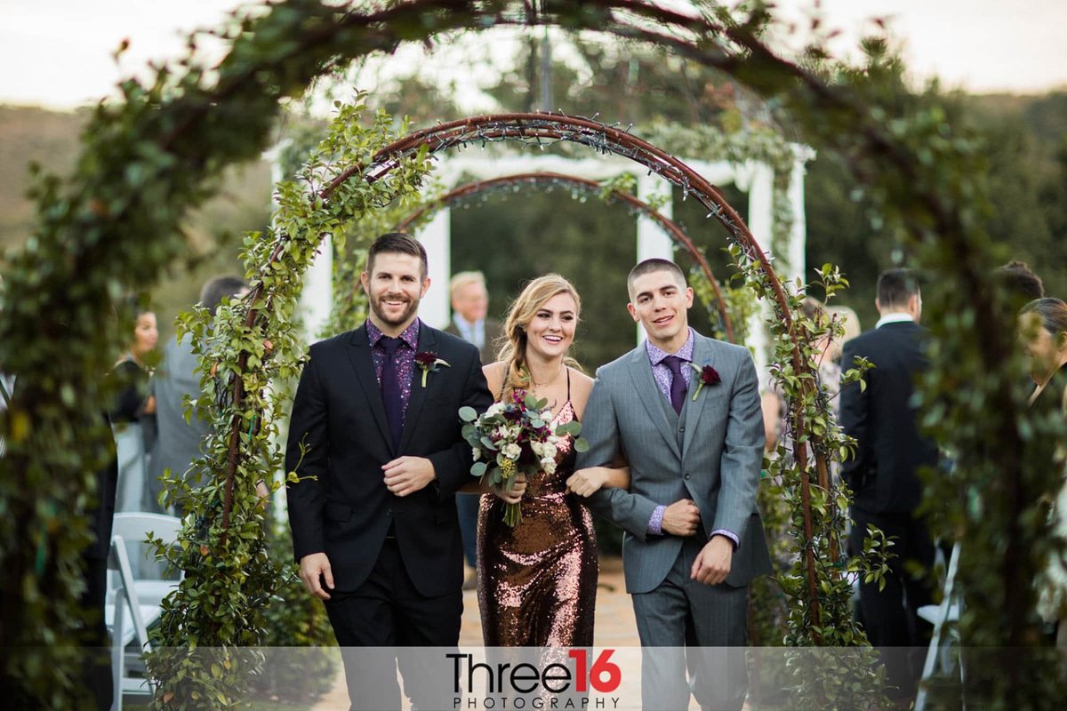 Maid of Honor being escorted up the aisle by groomsmen