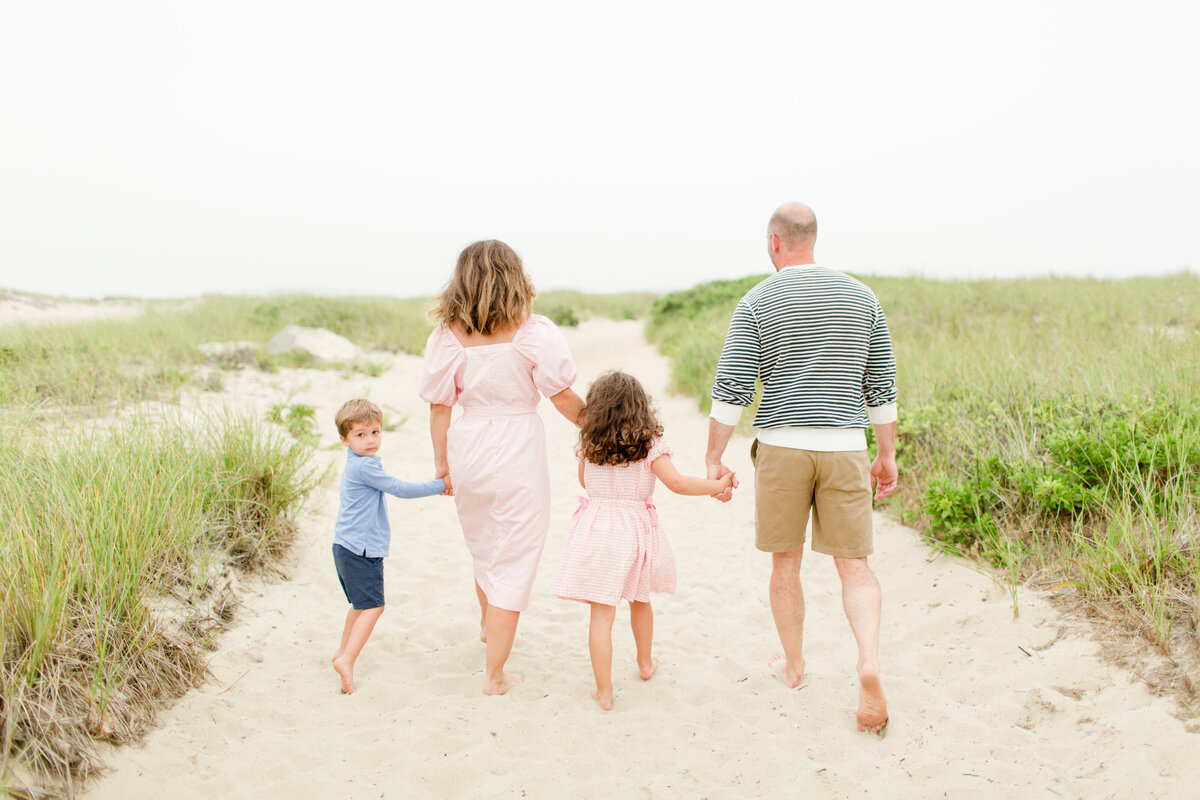 Young family running along the beach for a family photo session in the Boston area near Cape Cod