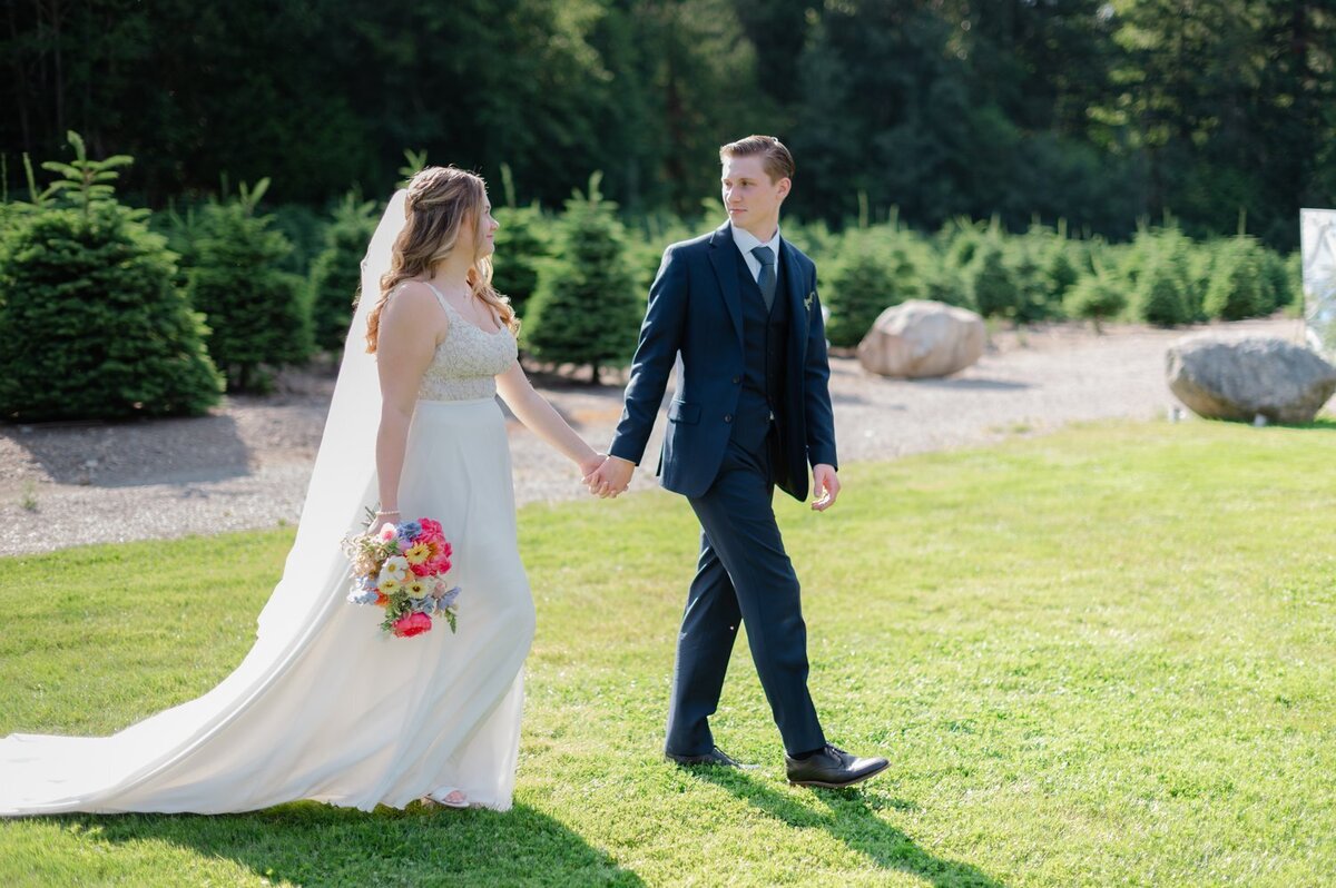 bride and groom holding hands and walking at trinity tree farm issaquah wedding venue