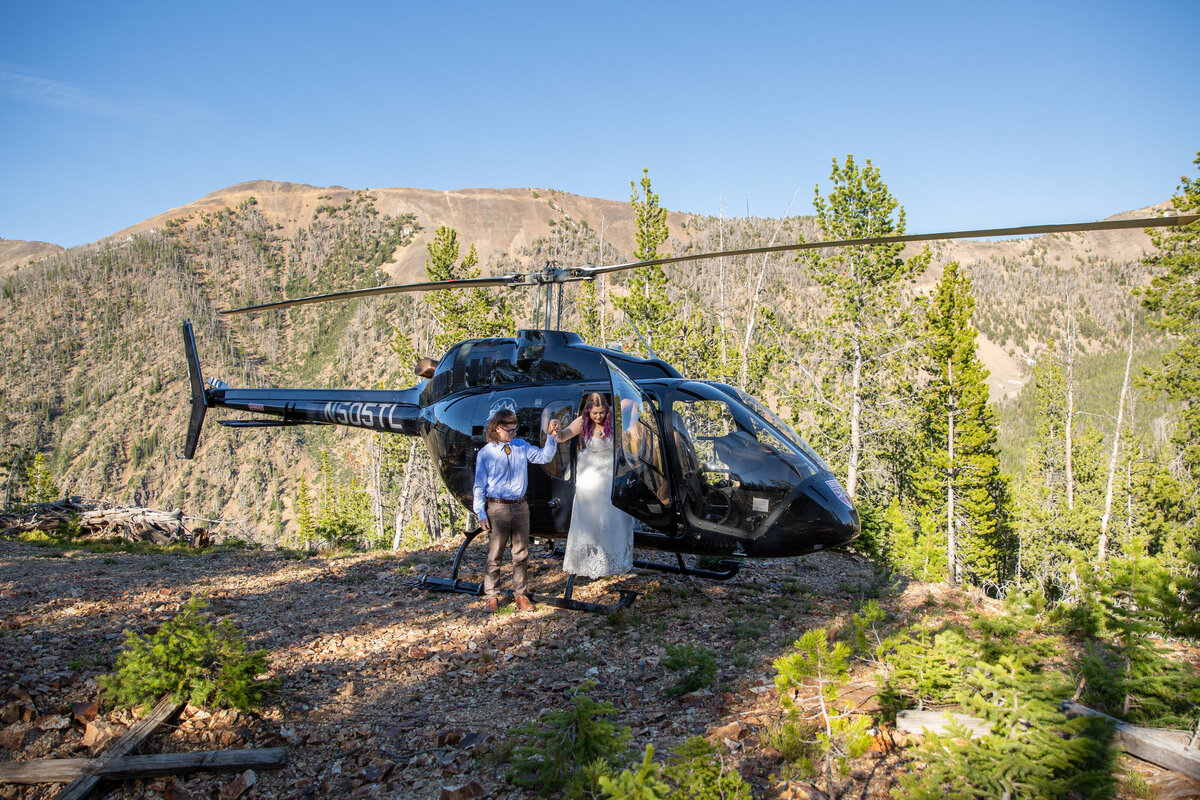 A groom helps his bride out of a helicopter on their elopement day in Montana.