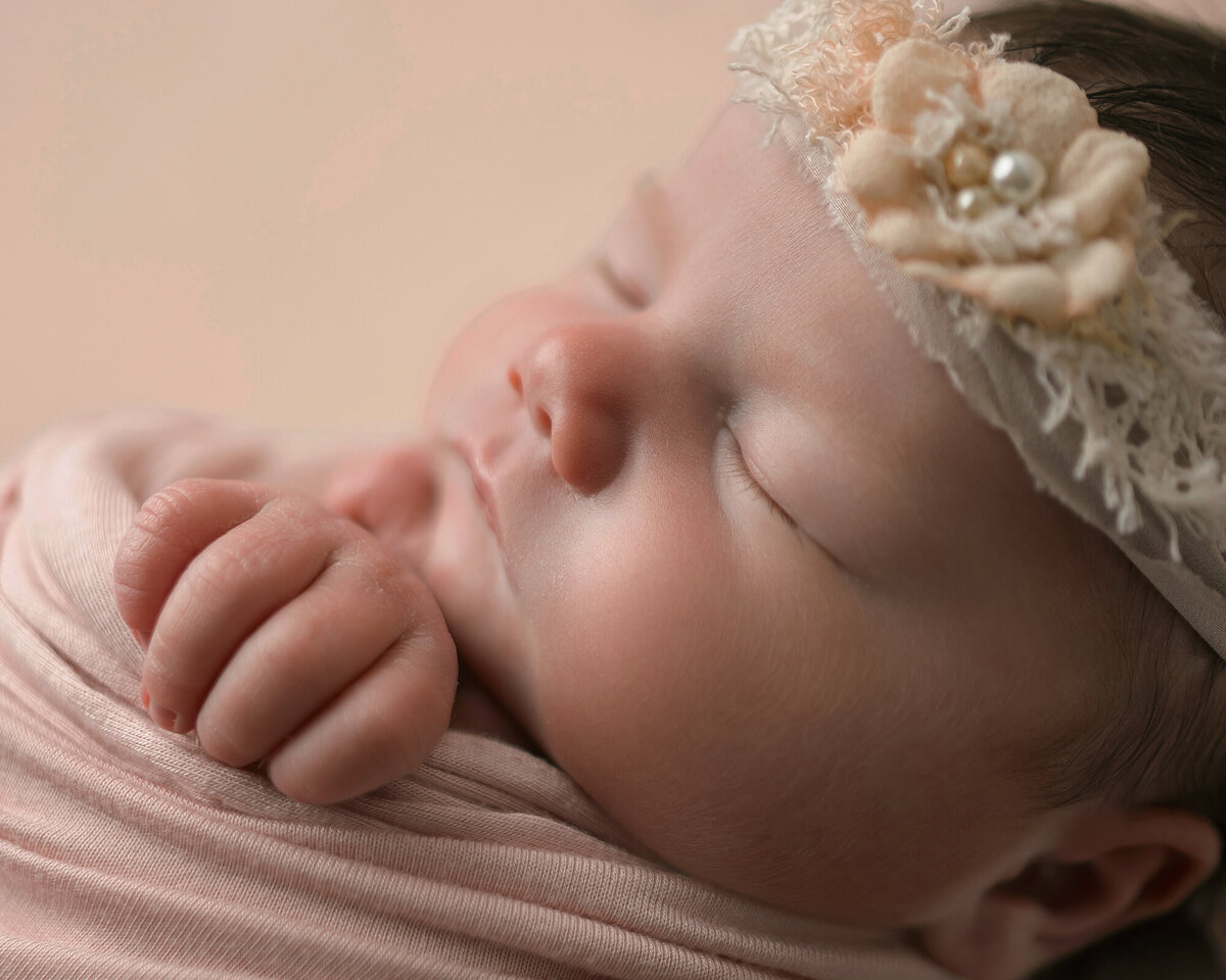 A newborn baby sleeping in a floral headband