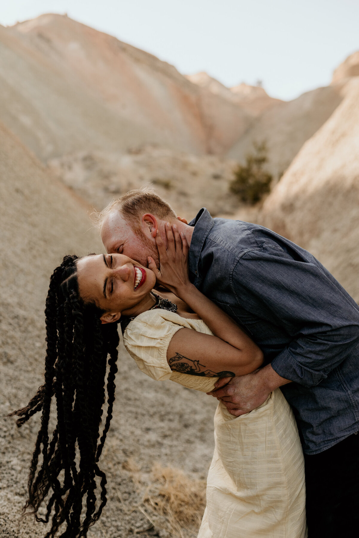 mand an woman holding each other and swaying and kissing amongst colorful rocks