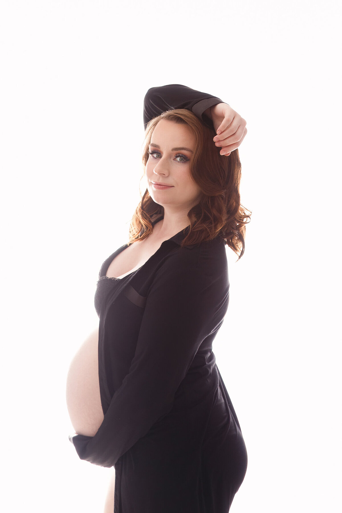 Pregnant woman wearing a black shirt photographed on a white background