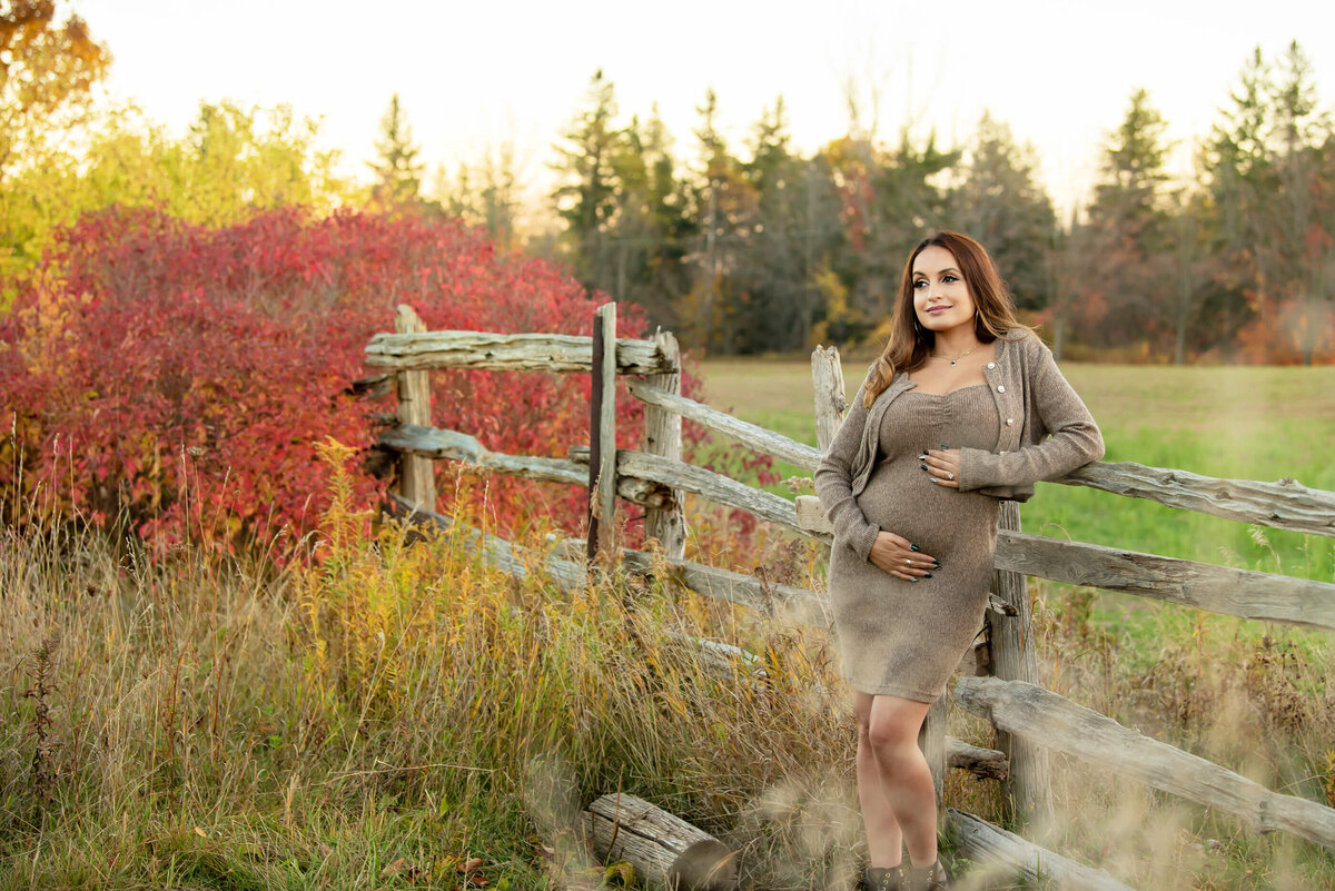 pregnant woman wearing a beige dress for her outdoor fall maternity photos