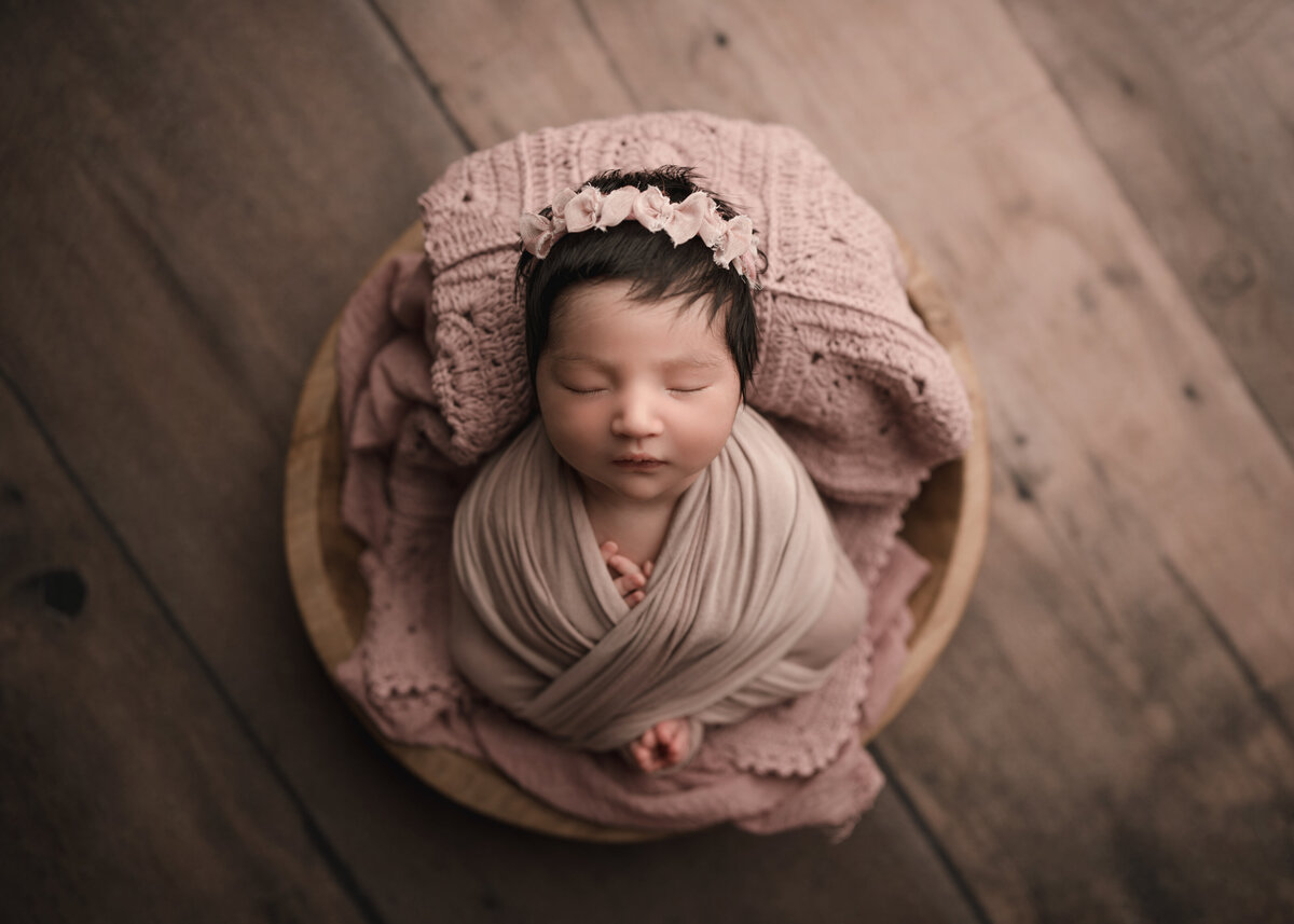 Aerial image of Riverside, CA newborn photoshoot. Baby girl wrapped in pink sleeping. Captured by Best Riverside, CA newborn photographer Bonny Lynn Photography.