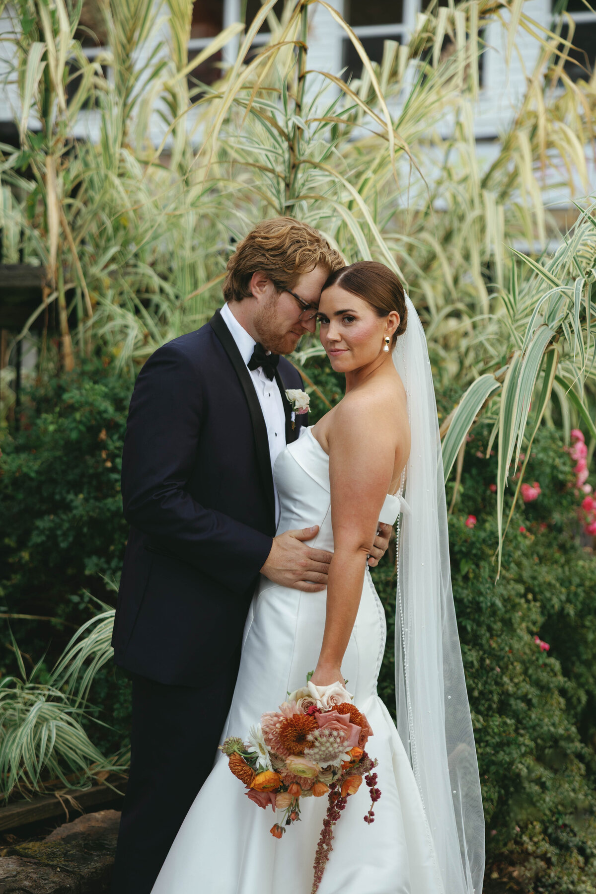 Bride and groom embracing in lush garden captured by Clar Barron Photo