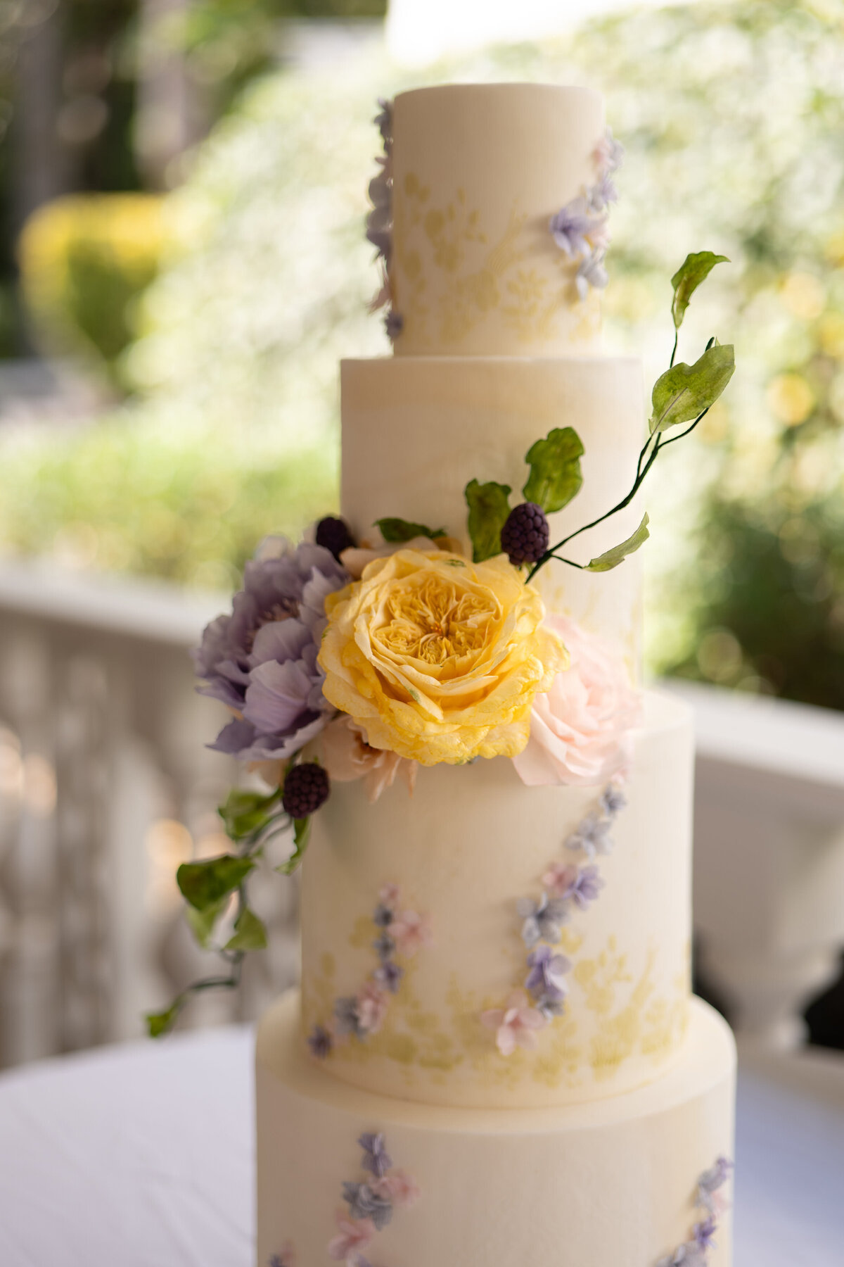 A tired wedding cake with flowers wrapping around it 