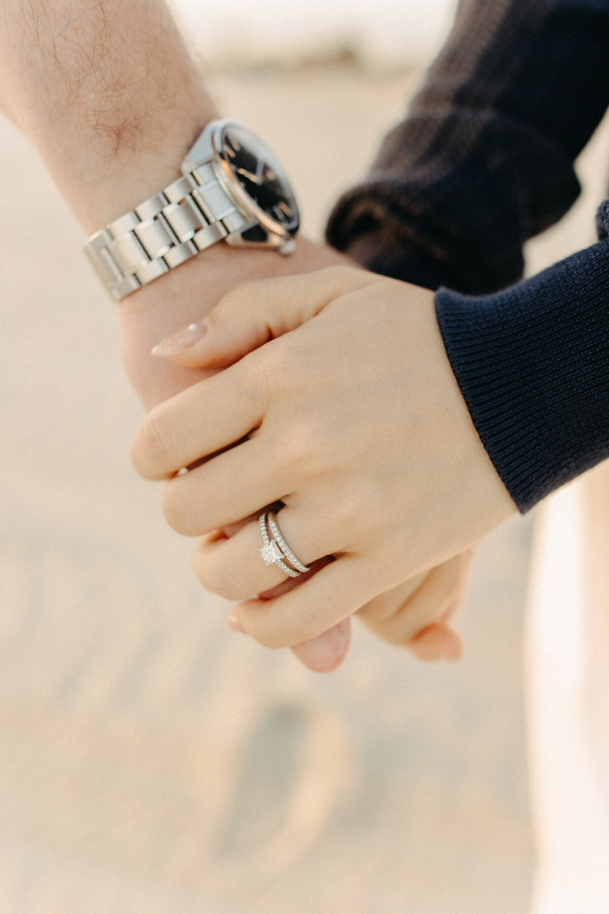 Detail shot of engagement ring while holding hands on the beach