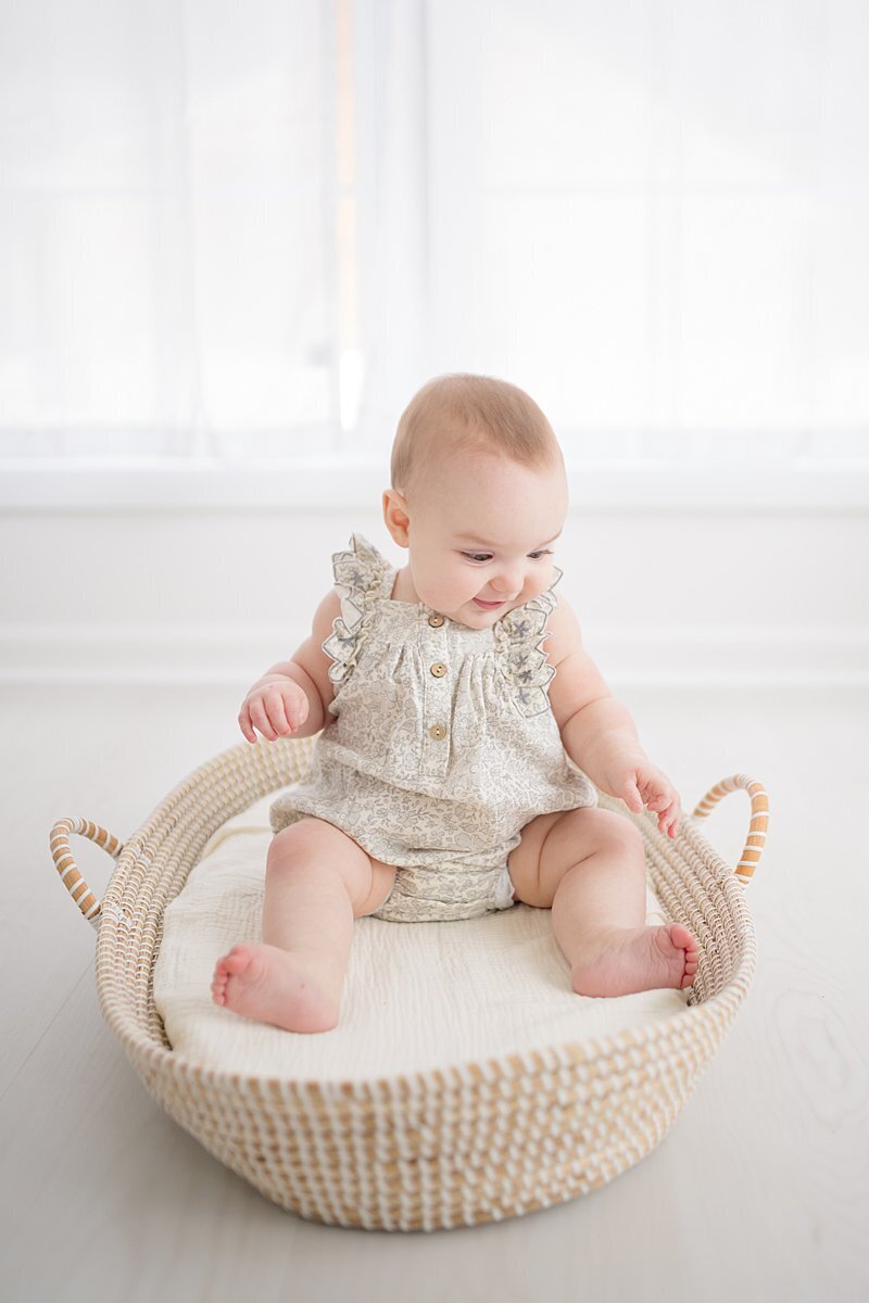baby girl in moses basket for 1st birthday photos in a portrait studio in stamford ct