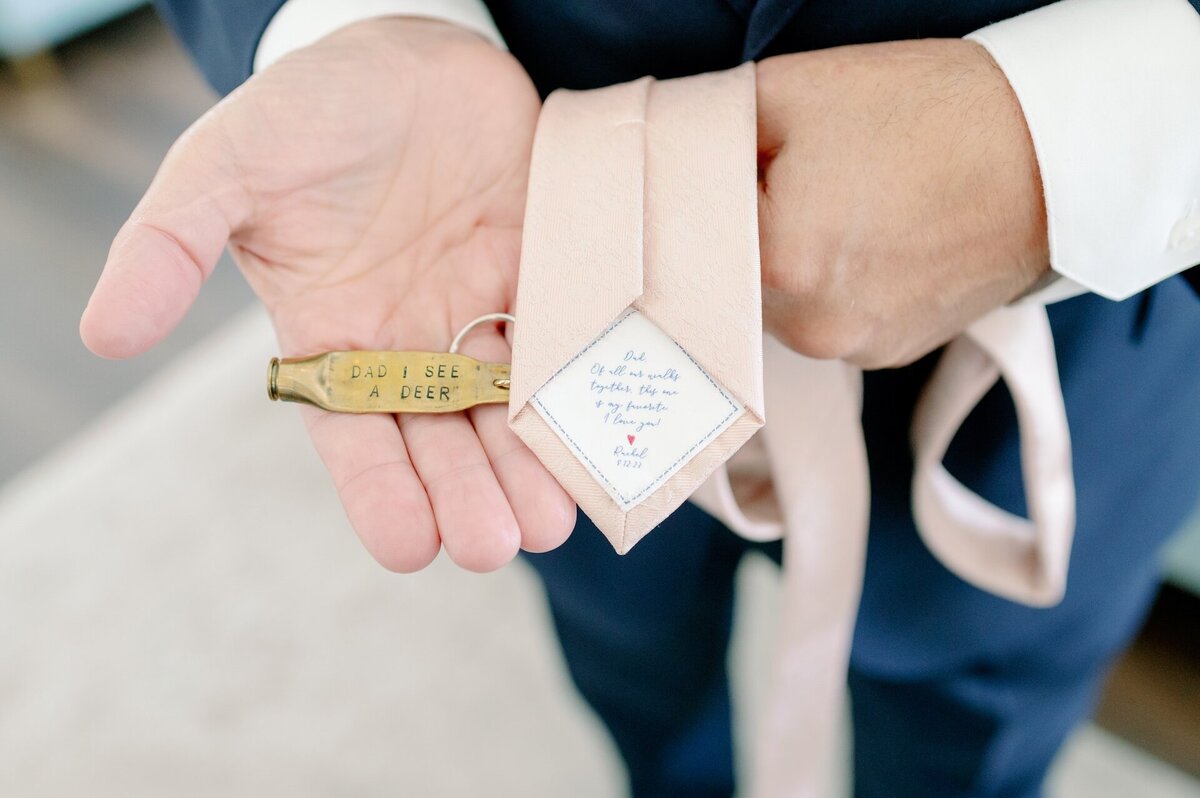 a groom showing a note on the inside of his tie