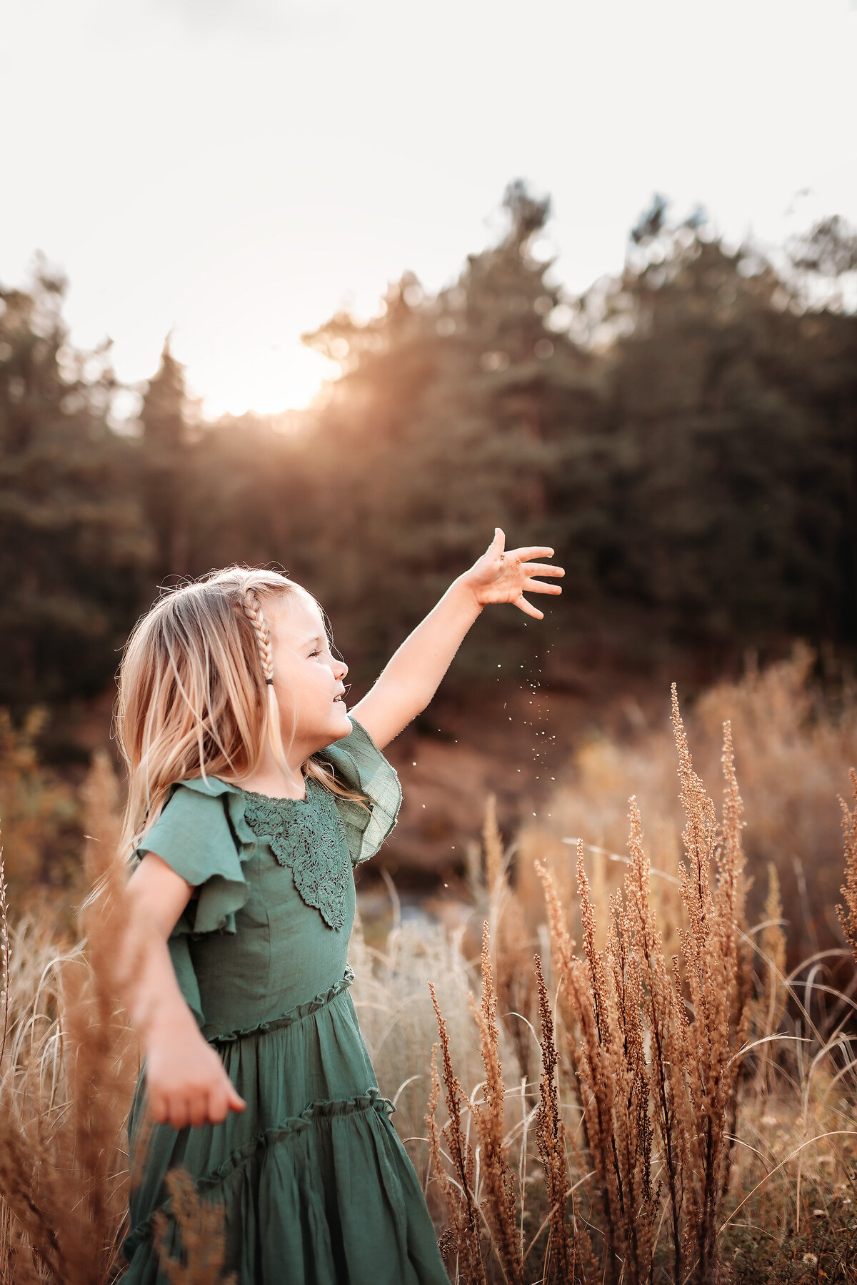 girl sprinkling grass seeds into the air in the sunlight