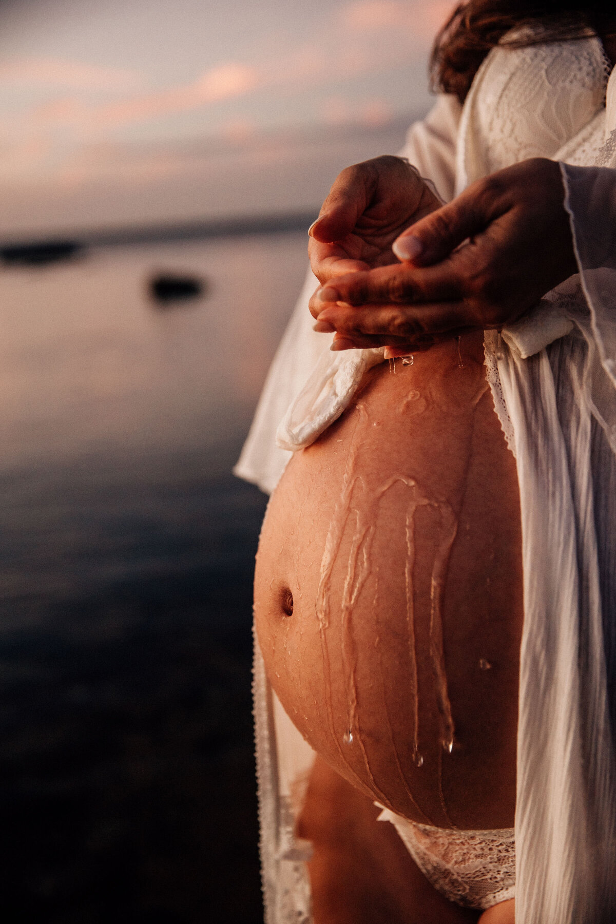 Lady drops water of pregnant belly at melbourne maternity photography session