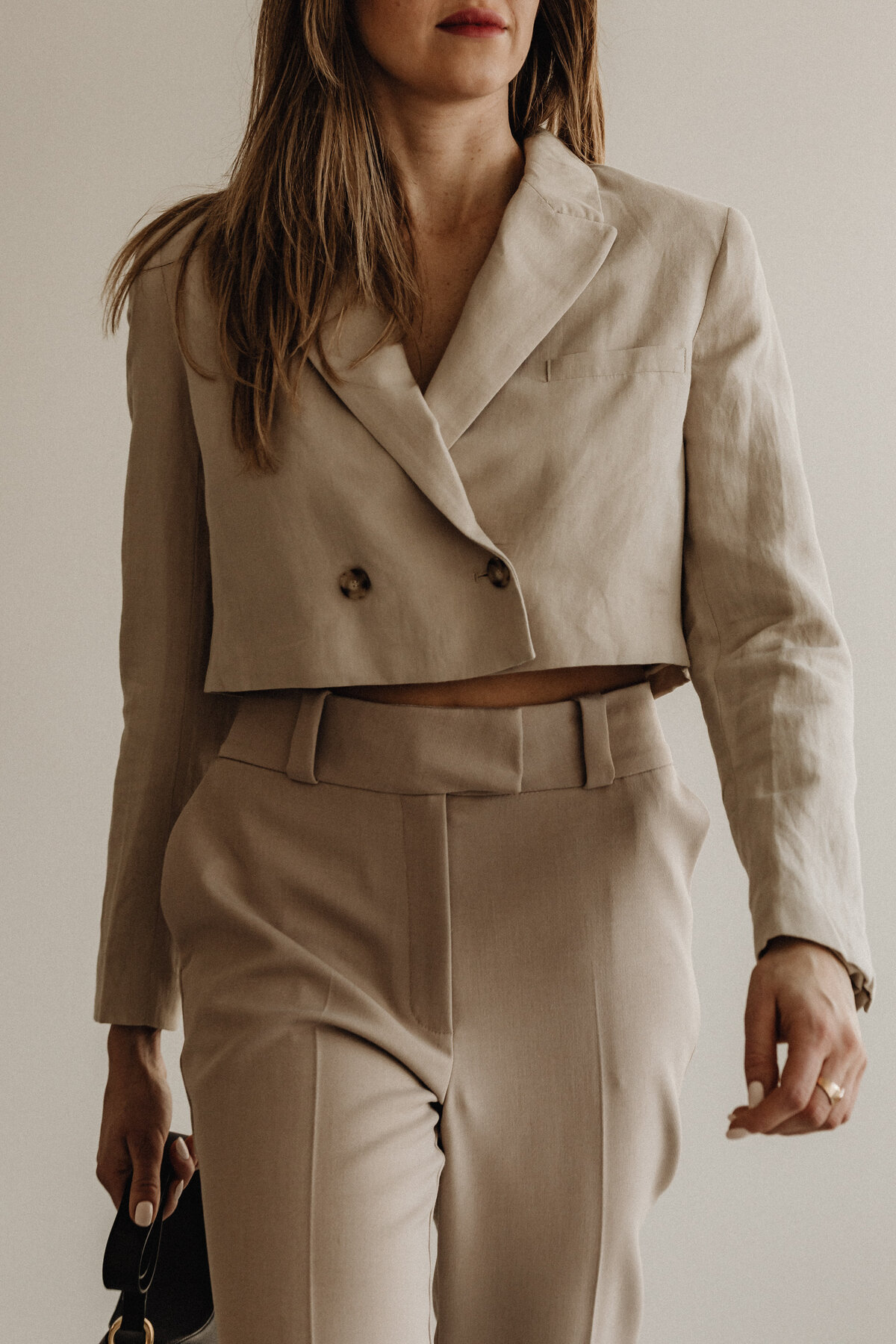 Frau mit beigen Blazer und Anzugshose.