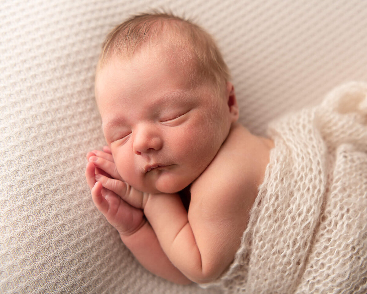 baby boy side-lying on beige fabric