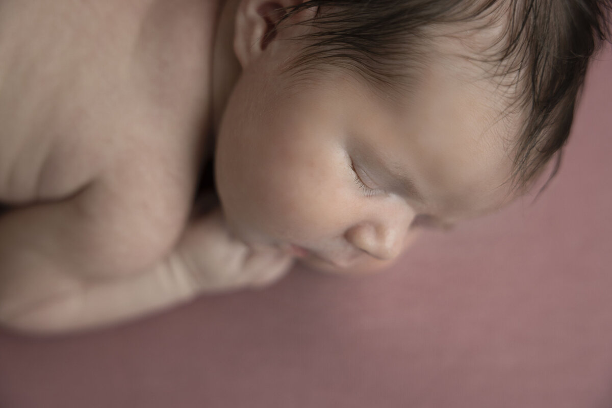 A side profile of a newborn girl highlights her gentle features.