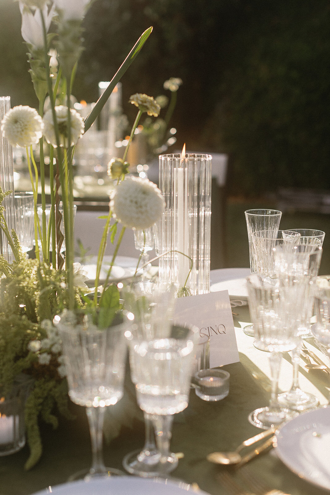 Centrepieces of modern white flowers are backlit in the sun at a Montreal wedding reception.