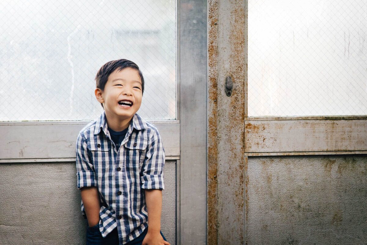 young boy laughing  in a greenhouse at berkeley botanical gardens.